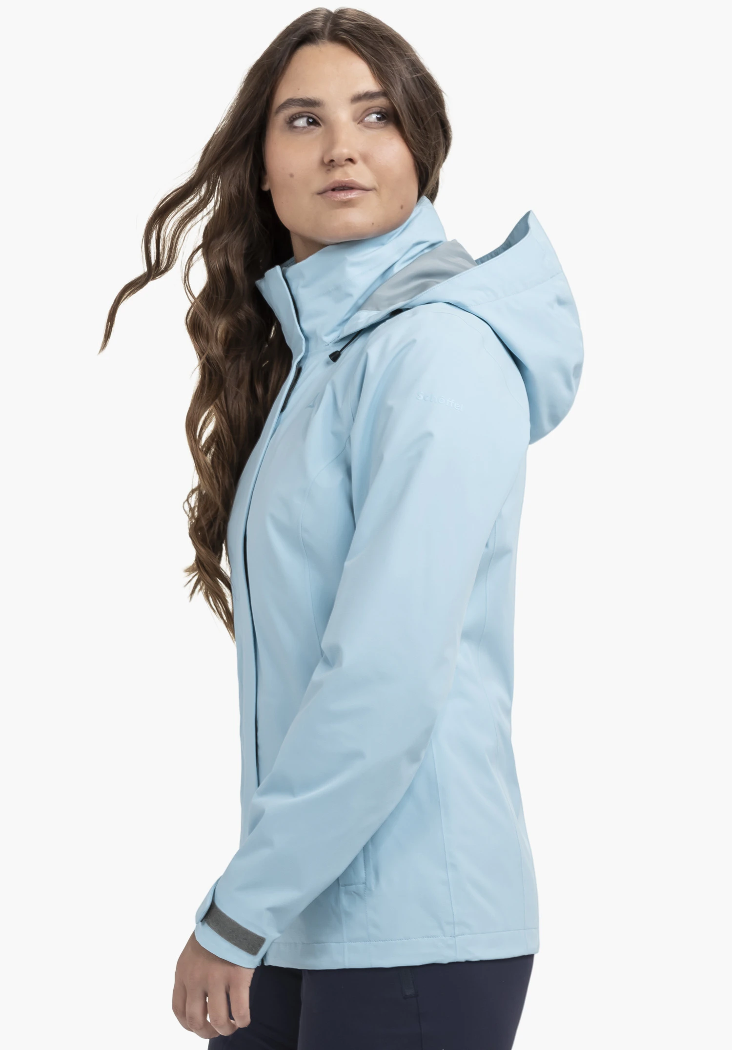 Jacket Gmund L portée par un mannequin se tenant de profil. La veste bleue est dotée d'une capuche et du logo Schöffel sur la manche gauche, photographiée sur un fond neutre.