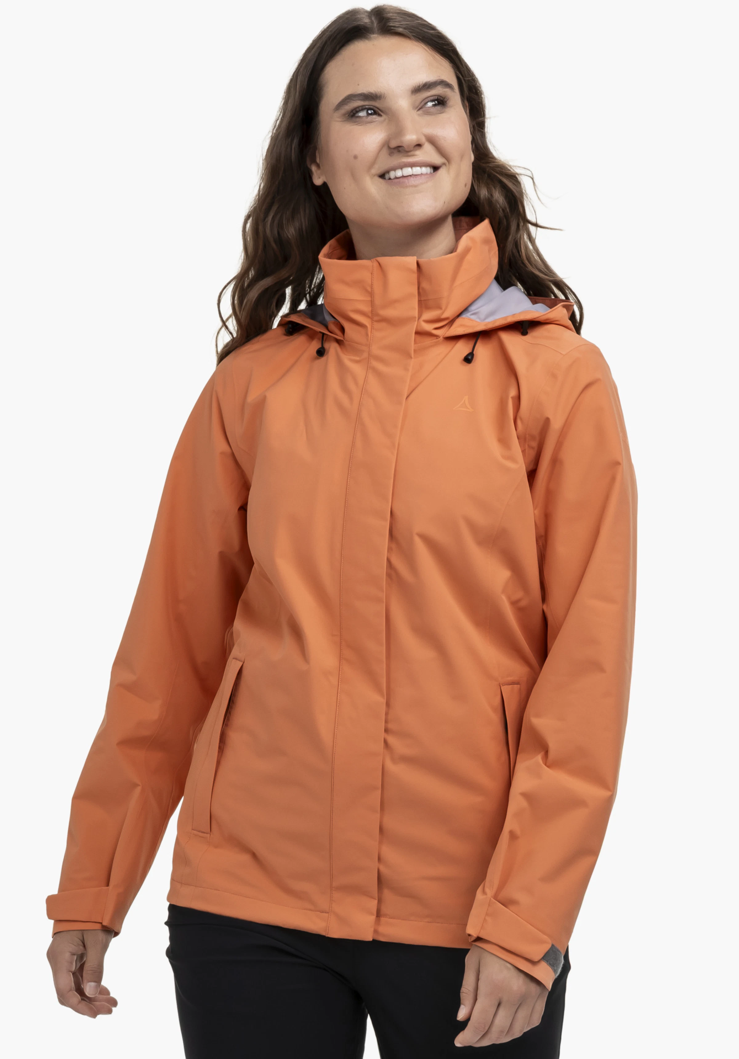 Jacket Gmund L in Orange getragen von einem Model. Das Model steht frontal, blickt lächelnd zur Seite und zeigt die Jacke mit hochgeschlossenem Kragen sowie einem dezenten Schöffel-Logo auf der linken Brust vor einem neutralen Hintergrund.