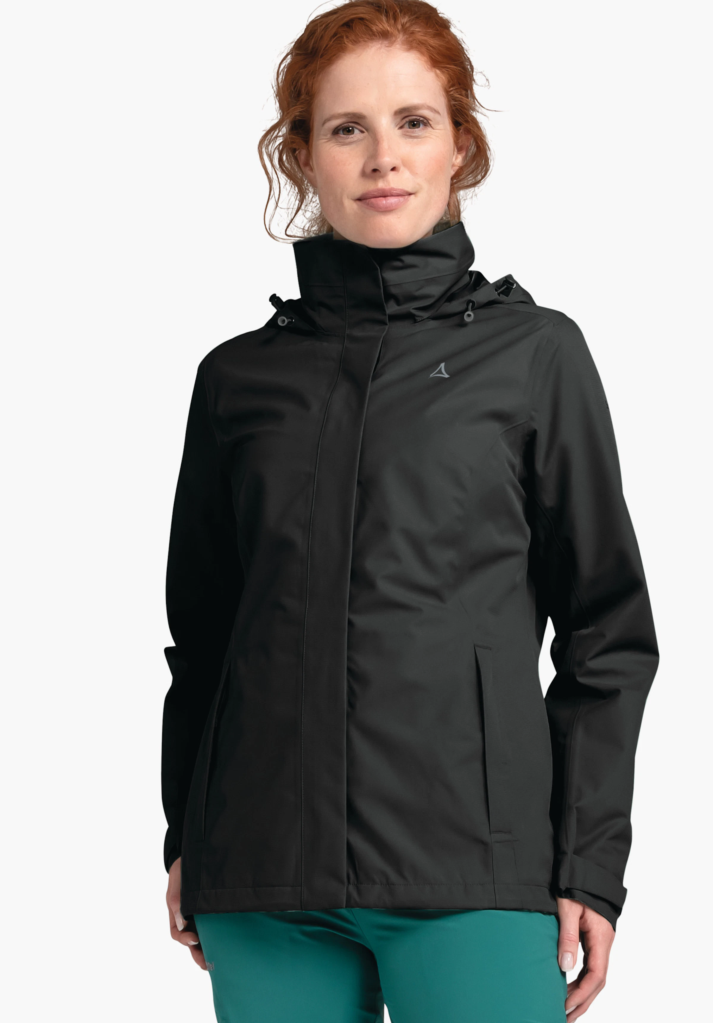 Jacket Gmund L Schwarze Regenjacke, getragen von Frau mit rotem Haar, Schöffel-Logo auf der Brust, frontal stehend vor hellem Hintergrund; trägt grüne Hose.