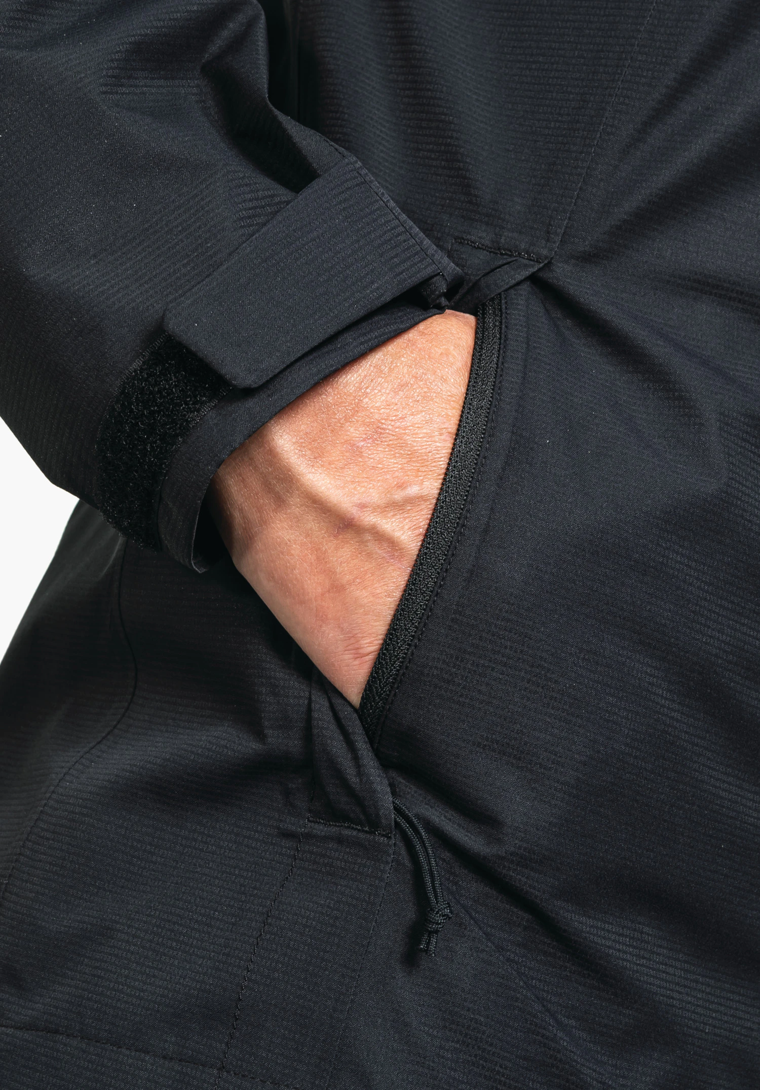 Jacket Gmund L, detailweergave van de zijzak met rits en de verstelbare manchet van zwarte functionele stof, close-up voor een witte/neutrale achtergrond.