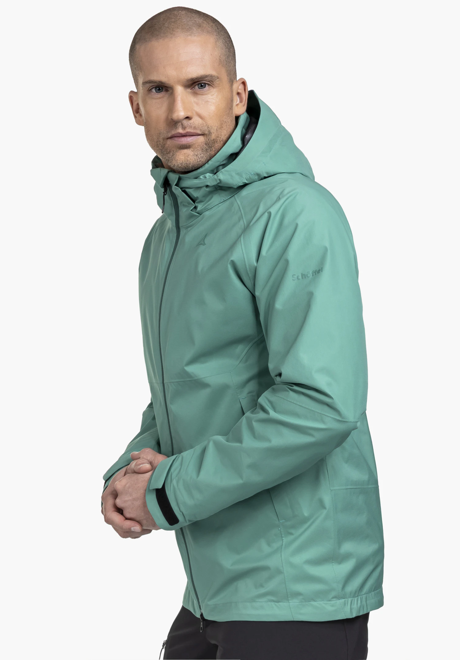 Jacket Easy XT M gedragen door een model dat zijdelings staat. De groene jas toont het Schöffel-Logo op de linkermouw, gefotografeerd tegen een neutrale achtergrond.