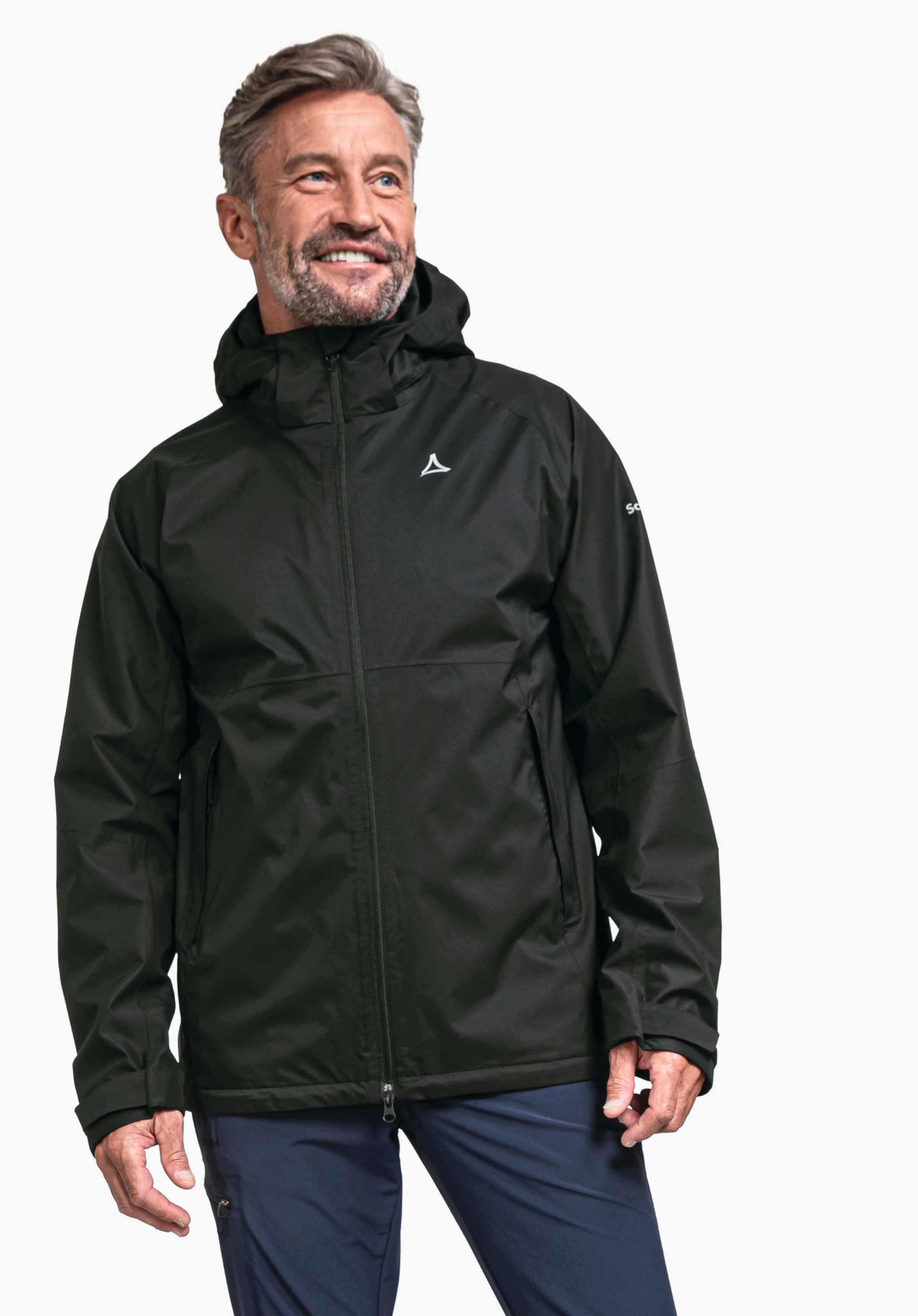 Jacket Easy XT M en noir classique, présenté par un mannequin souriant sur un fond neutre. Le mannequin est photographié de trois-quarts, mettant en valeur la coupe fonctionnelle, tandis que le logo Schöffel blanc est subtilement visible sur la poitrine.
