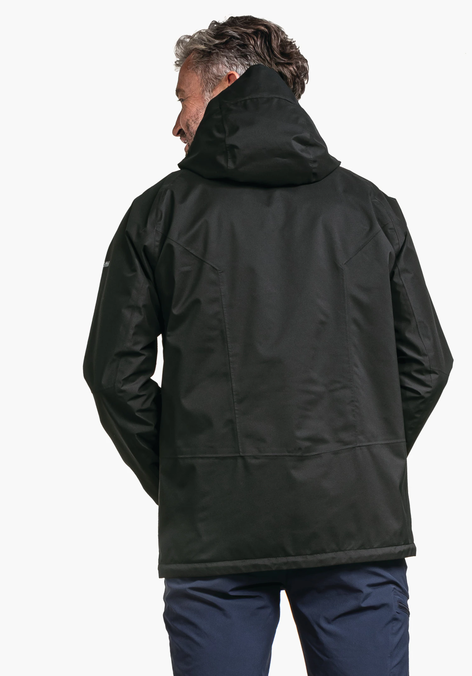 Jacket Easy XT M en noir, présentée en vue de dos sur un mannequin avec la capuche relevée et le logo Schöffel visible sur la manche sur un fond neutre.