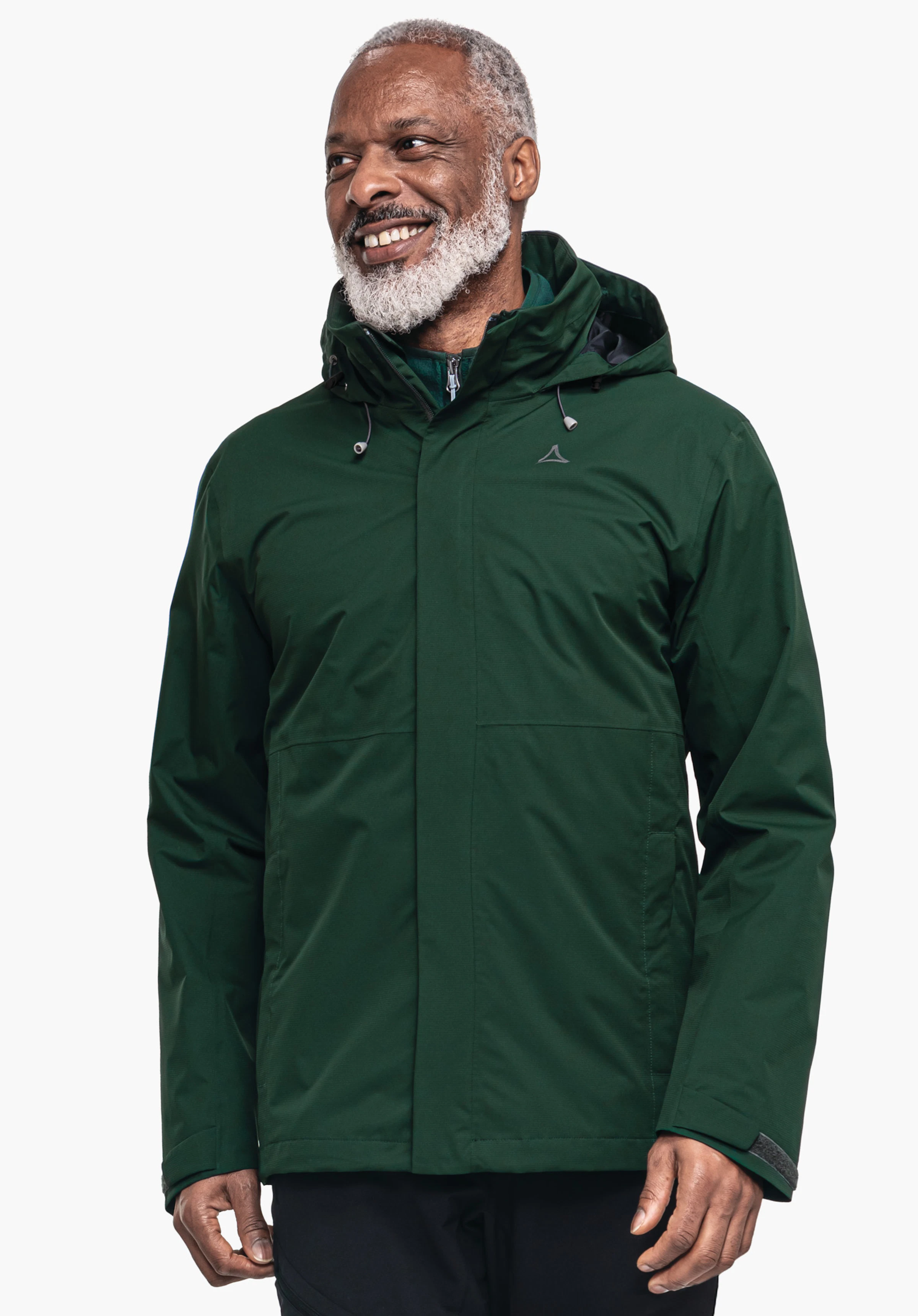 Jacket Gmund M Veste vert foncé portée par un homme souriant avec barbe blanche; logo Schöffel sur la poitrine; capuche resserrée; debout devant un fond blanc uni.