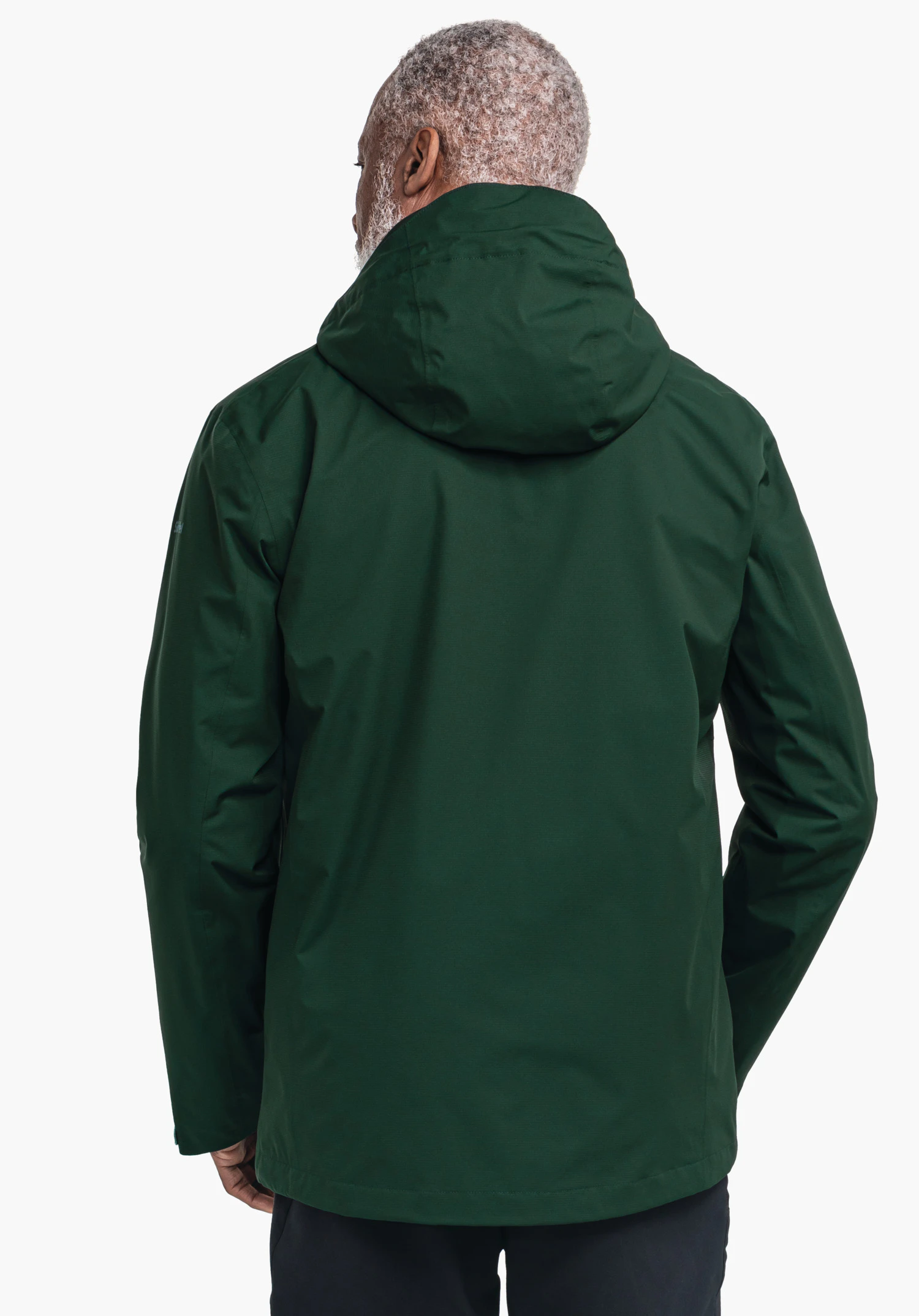 Jacket Gmund M veste vert foncé, portée par une personne (vue de dos); la capuche repose sur les épaules; la personne se tient calmement devant un fond clair et uni.