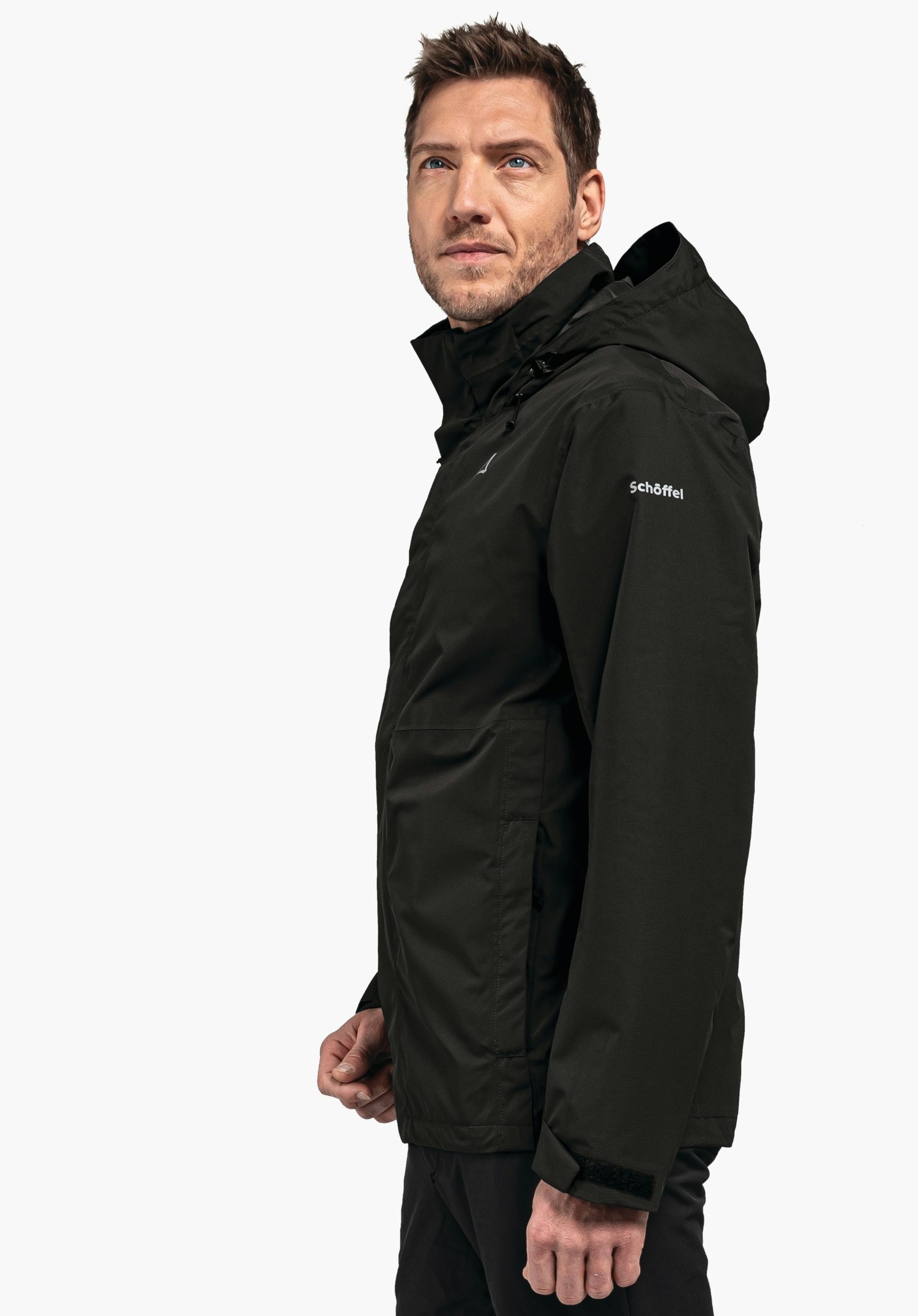 Jacket Gmund M black jacket worn by a man standing side-on, looking slightly upwards to the right in front of a white background. Text on sleeve: "Schöffel". Schöffel logo visible on chest.