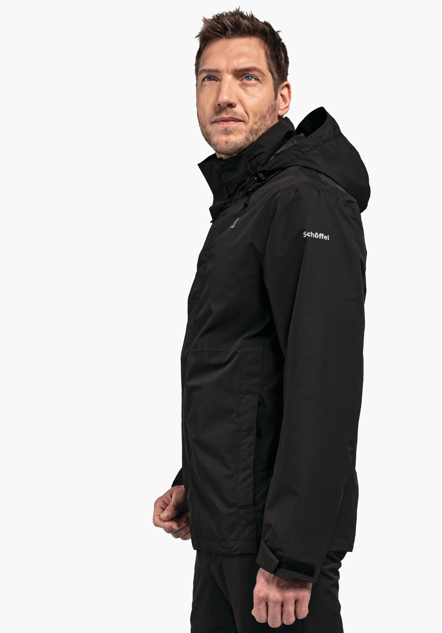 Jacket Gmund M black jacket worn by a man standing side-on, looking slightly upwards to the right in front of a white background. Text on sleeve: "Schöffel". Schöffel logo visible on chest.