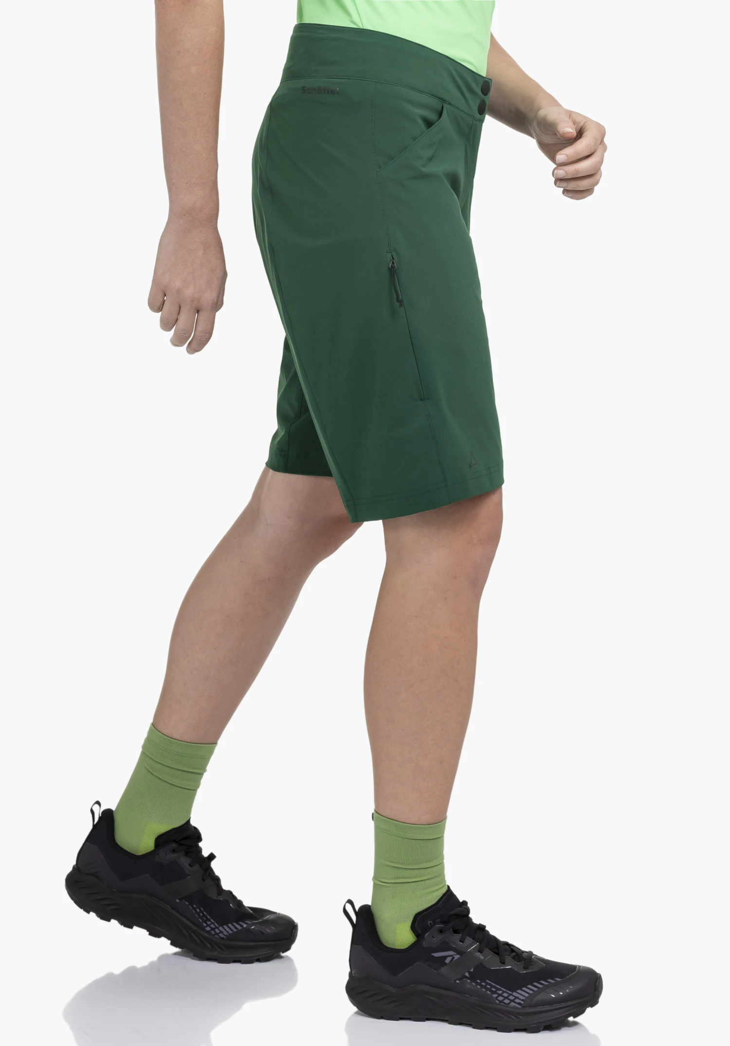 Shorts Danube L in Grün präsentiert an einer wandernden Person in Seitenansicht vor neutralem Hintergrund. Die Shorts besticht durch ihre funktionale Passform und ein dezentes Schöffel-Logo am Hosenbein.