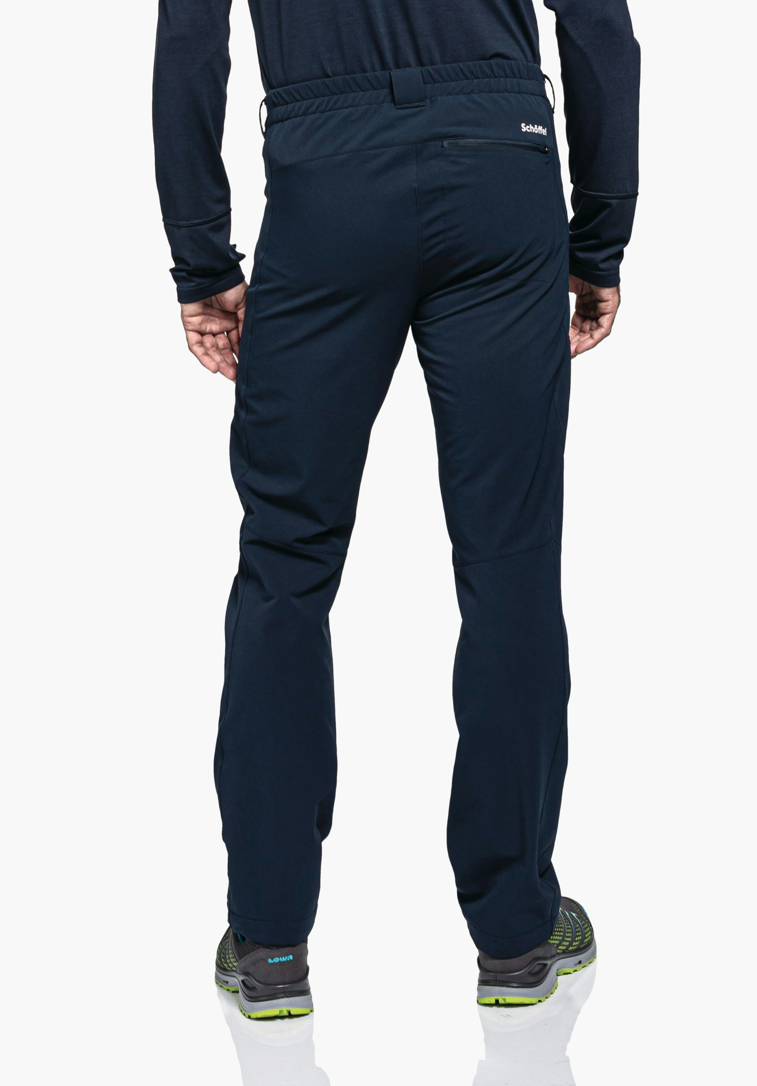 Pants Folkstone Warm M dark blue men’s trousers worn from the back; person standing on a white studio background, relaxed fit, right zip pocket with “Schöffel” text; grey hiking shoes.