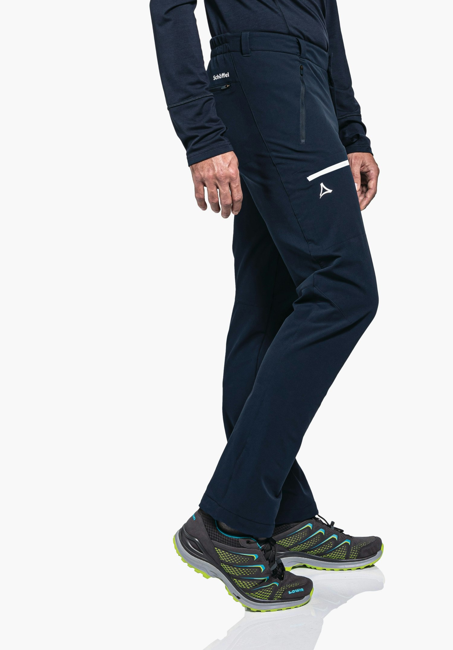 Pants Folkstone Warm M dark blue trekking trousers worn by a person standing slightly offset; right thigh with Schöffel logo and lettering "Schöffel"; grey shoes with light green sole and lettering "LOWA"; white background.
