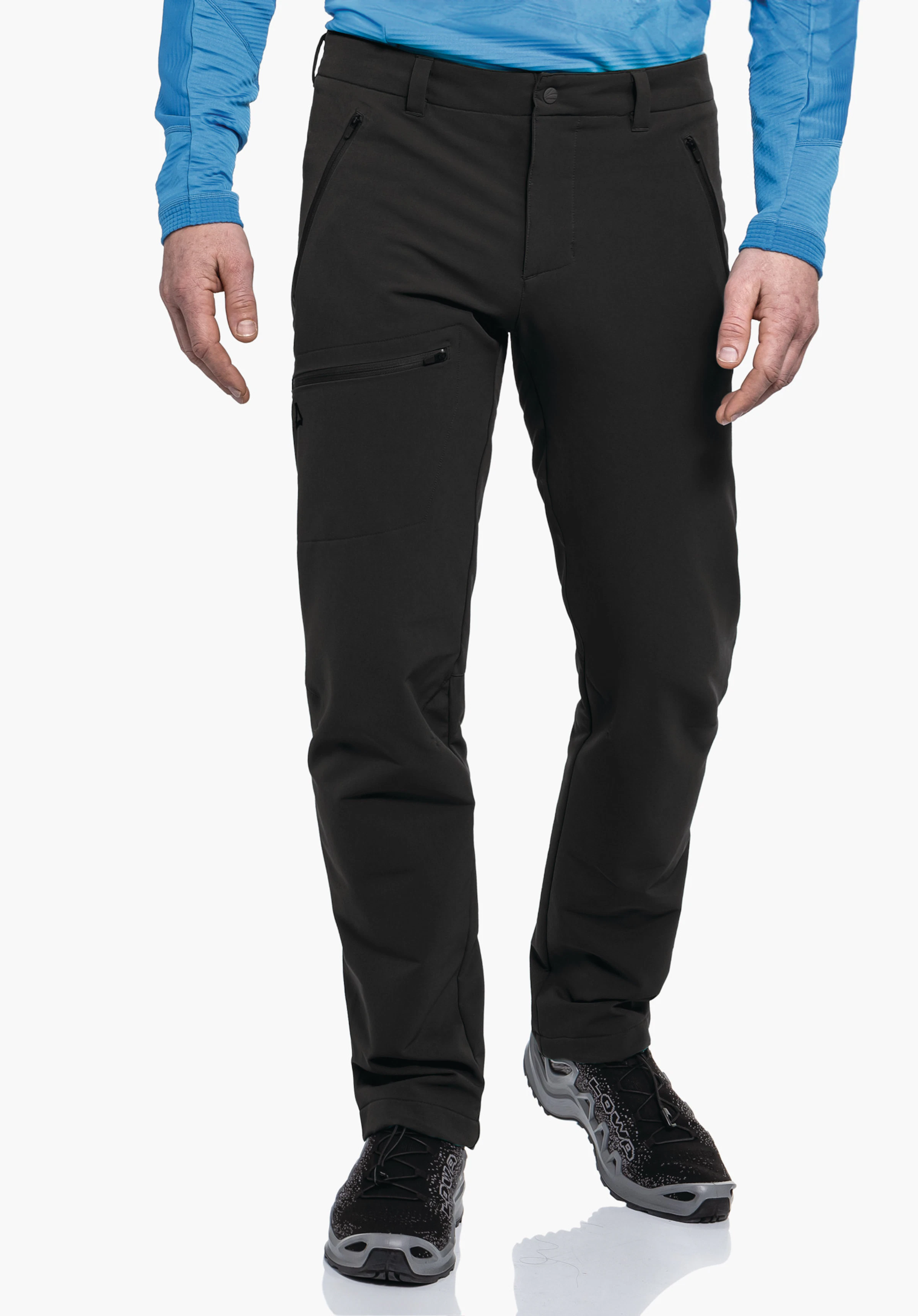 Pants Folkstone Warm M Schwarze Hose mit Reißverschlusstasche und Schöffel-Logo, von einer stehenden Person getragen; Kontext: weißer Studiohintergrund, Person trägt hellblaues Langarmshirt und schwarz-graue Wanderschuhe.