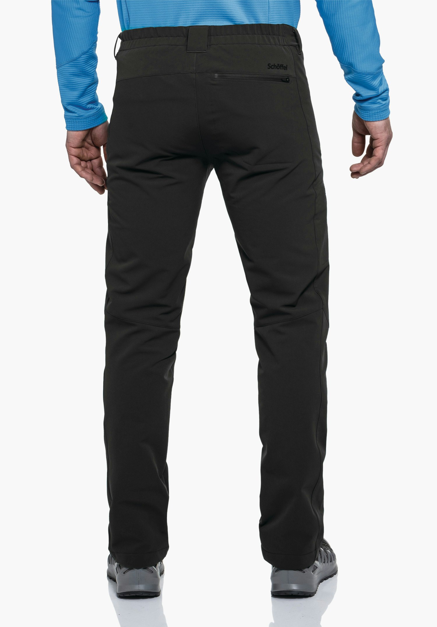 Pants Folkstone Warm M Schwarze Hose, Rückenansicht, getragen von stehendem Mann; Hecktasche mit Schrift "Schöffel"; hellblaues Oberteil, weißer Hintergrund, graue Schuhe.