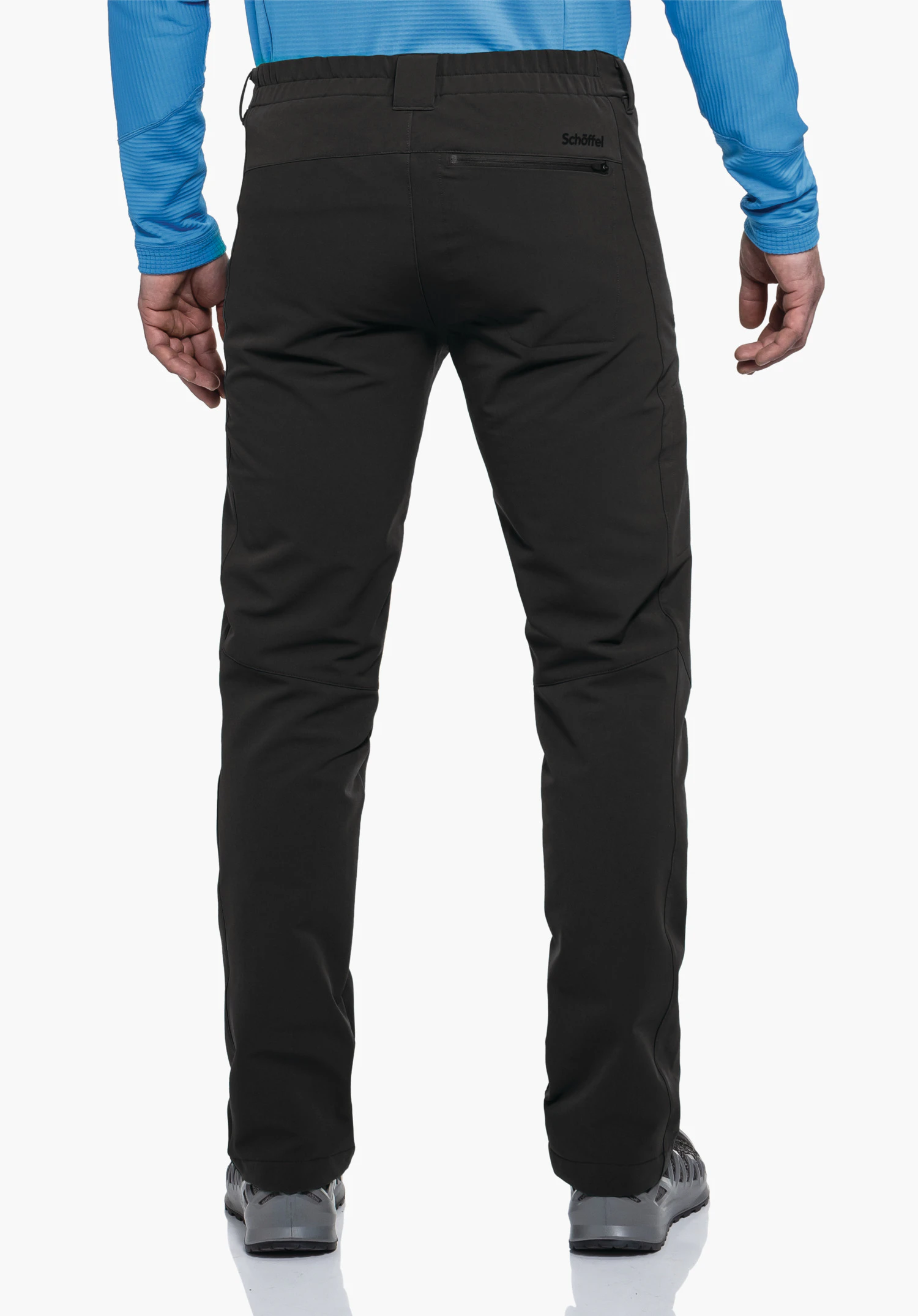 Pants Folkstone Warm M black trousers, rear view, worn by a standing man; back pocket with “Schöffel” lettering; light blue top, white background, grey shoes., Pants Folkstone Warm M black trousers, rear view, worn by a standing man; back pocket with “Schöffel” lettering; light blue top, white background, grey shoes.