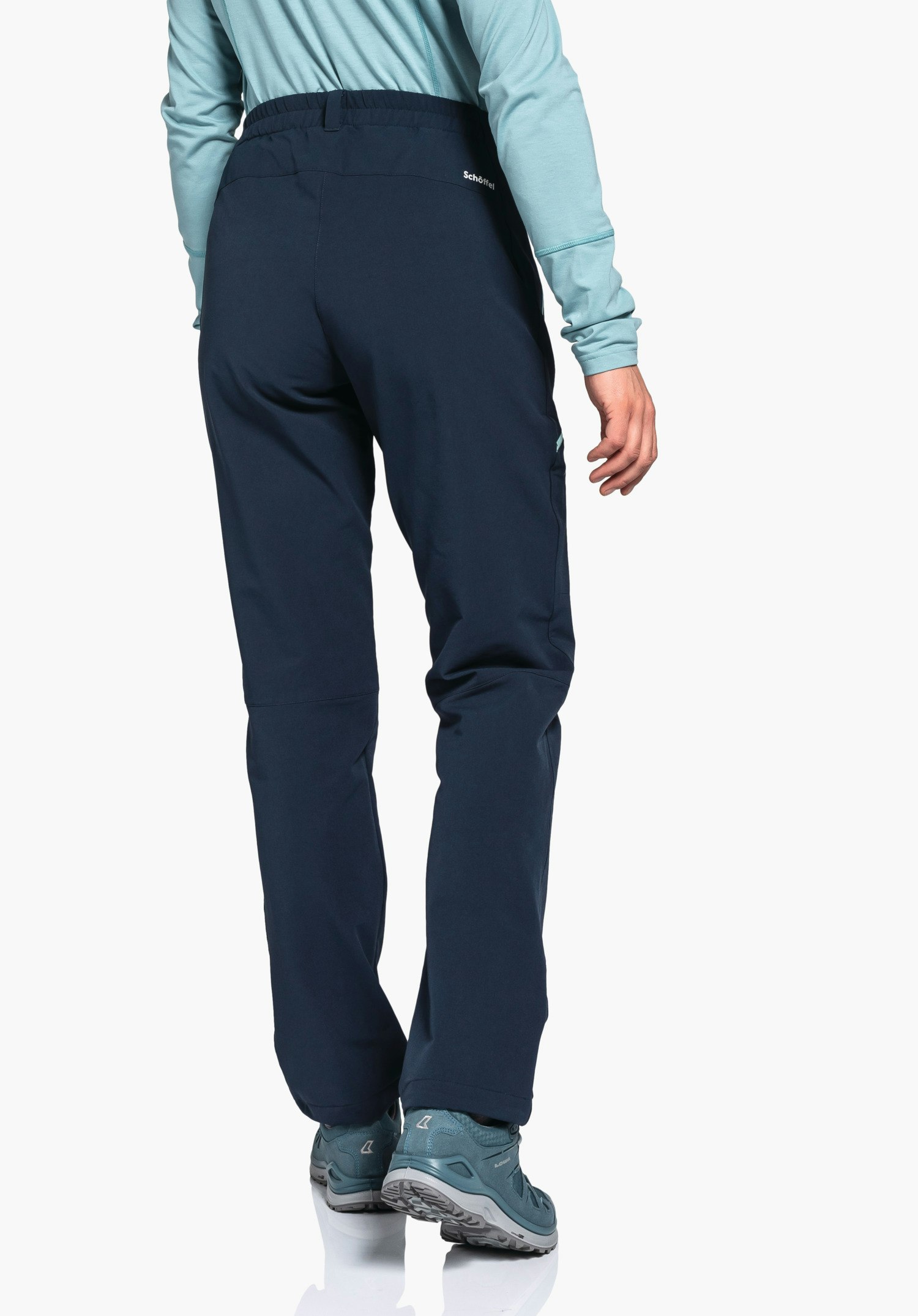 Pants Ascona Warm L Dunkelblaue Outdoorhose, getragen von Person, steht mit Rücken zur Kamera; hellblaues Langarmshirt und hellblaue Wanderschuhe, weißer Hintergrund. Text: "Schöffel".