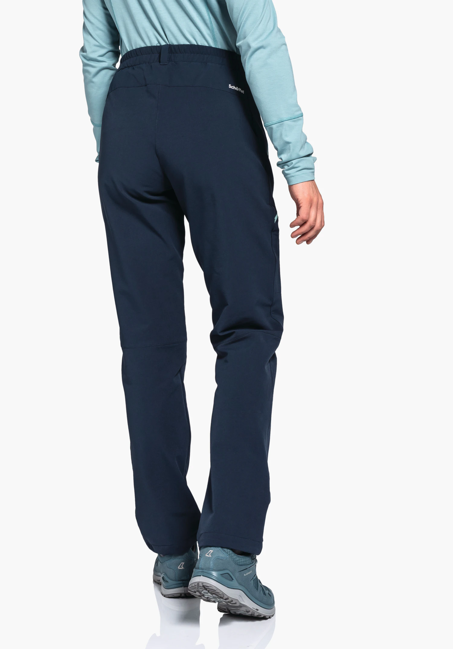 Pants Ascona Warm L Dunkelblaue Outdoorhose, getragen von Person, steht mit Rücken zur Kamera; hellblaues Langarmshirt und hellblaue Wanderschuhe, weißer Hintergrund. Text: "Schöffel".