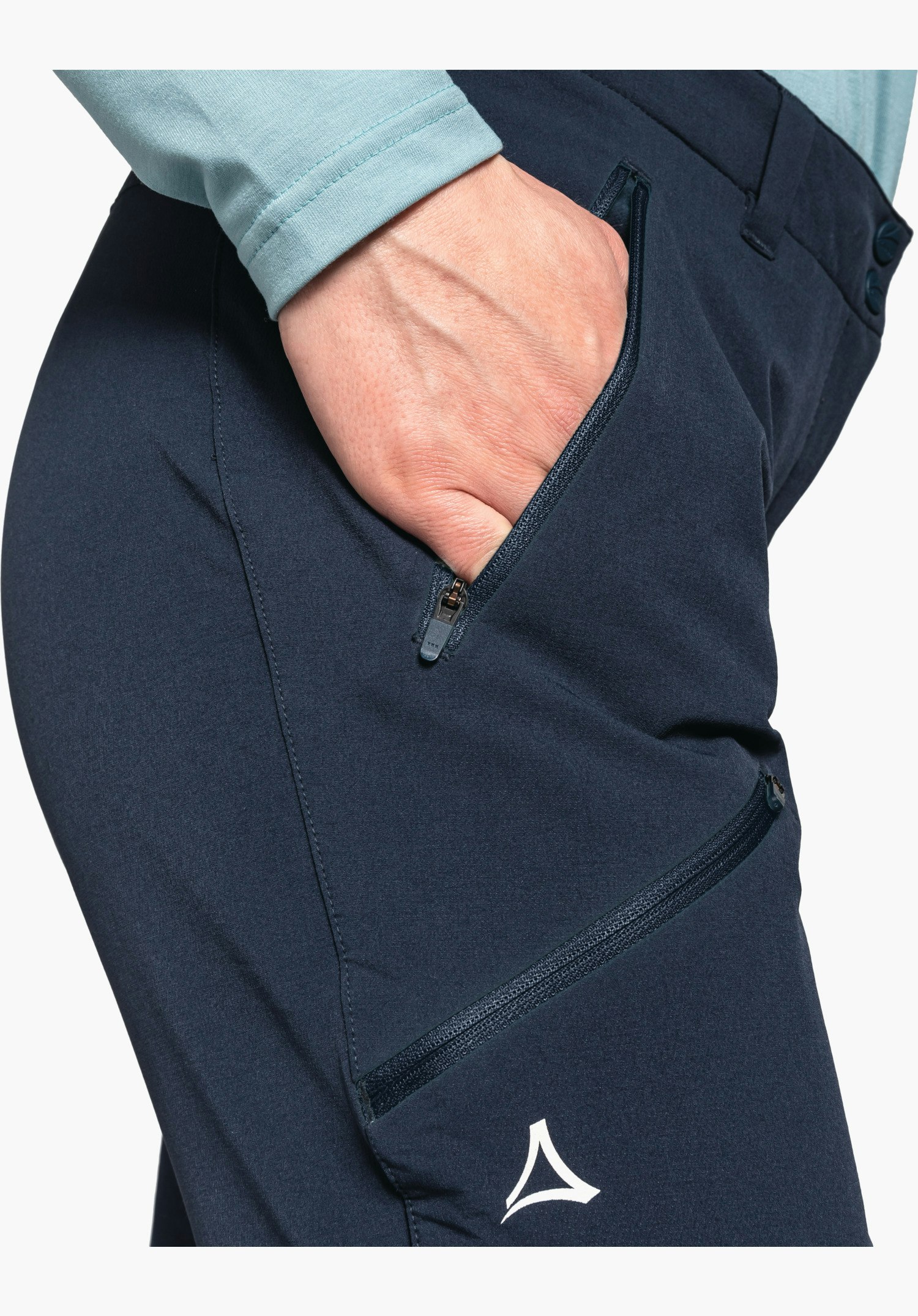 Pants Ascona Warm L zeigt die seitlichen Reißverschlusstaschen und das weiße Schöffel-Logo auf dem blauen Material, Nahaufnahme vor weißem/neutralem Hintergrund.