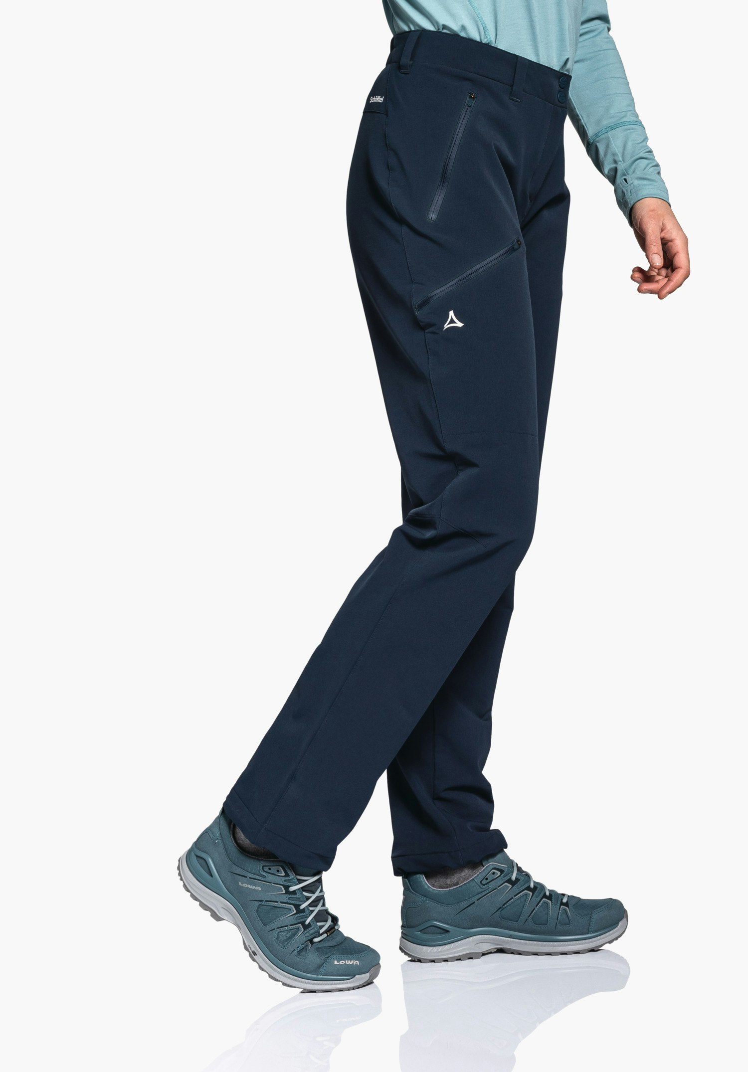 Pants Ascona Warm L dunkelblaue Outdoorhose mit Schöffel-Logo, Beine überkreuzt in Gehstellung; Kontext: hellblaues Langarmshirt und hellblaue Trekkingschuhe vor weißem Hintergrund. Text: "Schöffel", "LOWA".