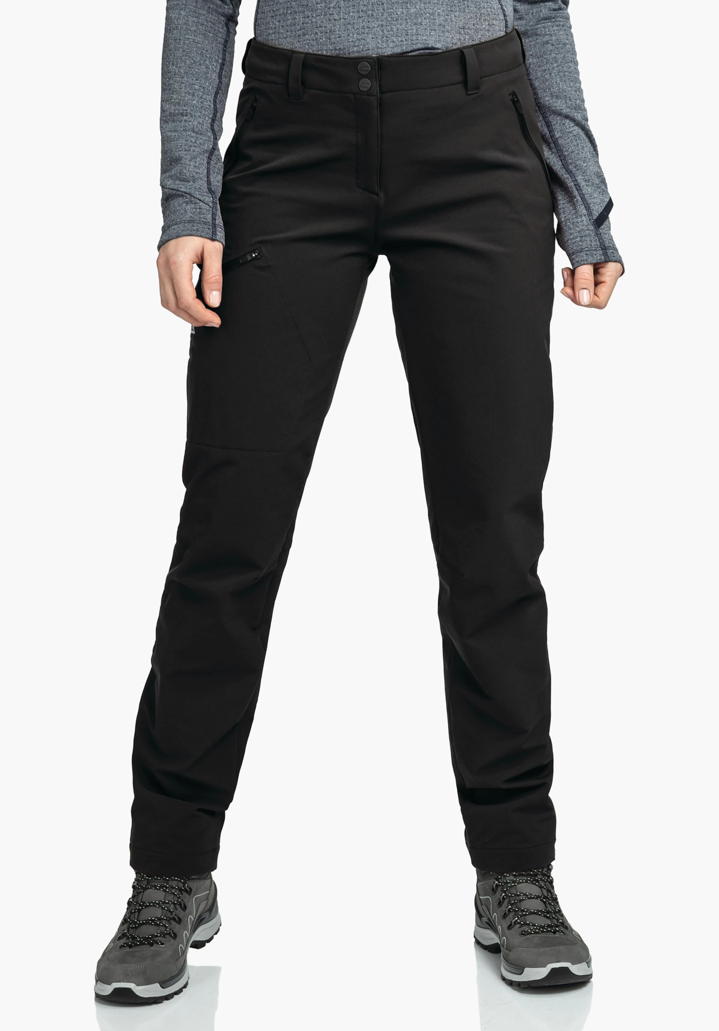Pants Ascona Warm L Schwarze Outdoor-Hose, getragen von stehender Person mit leicht gespreizten Beinen; Hände an den Seiten, Reißverschlusstasche am Oberschenkel, Wanderschuhe, weißer Hintergrund.