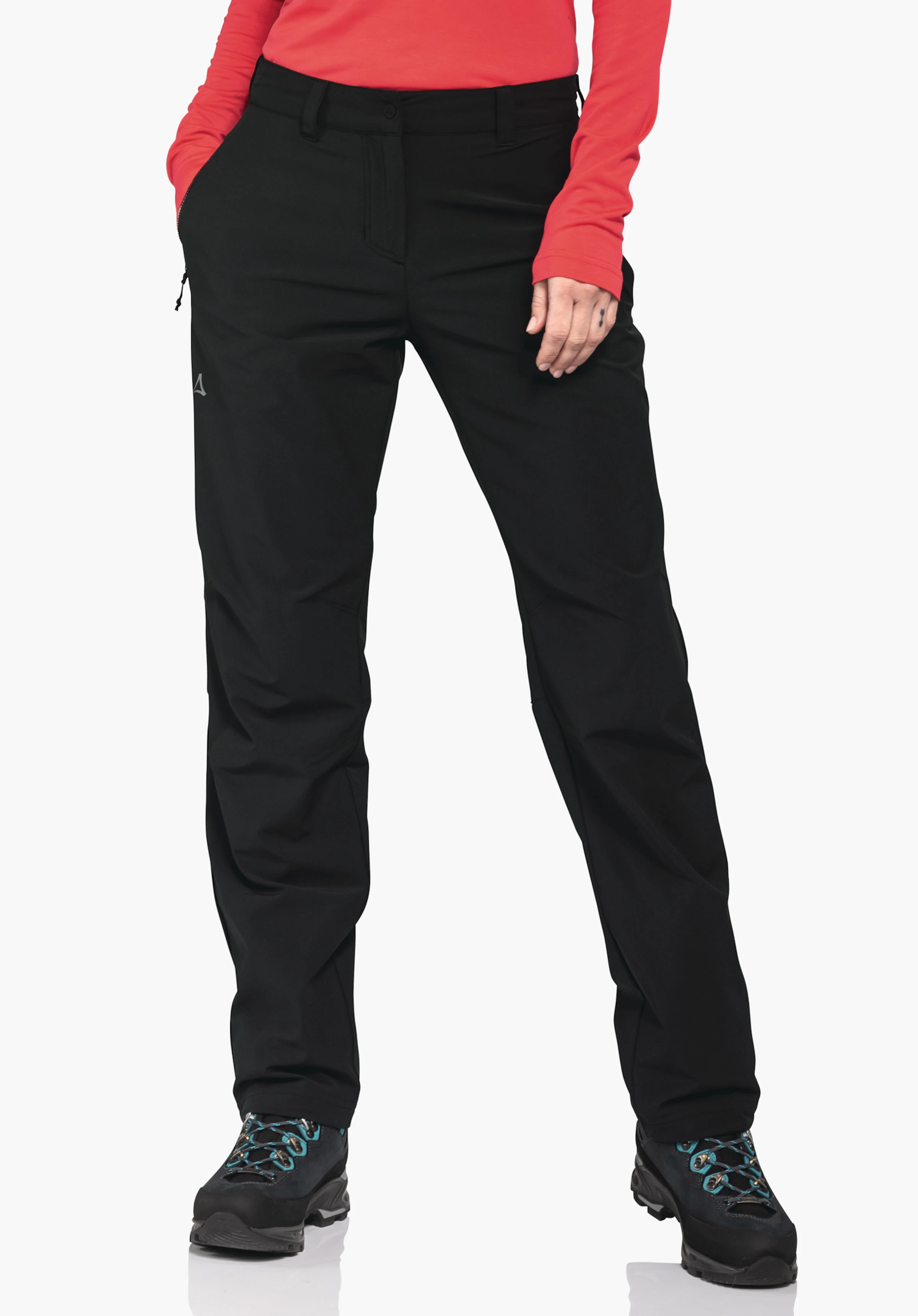 Pants Engadin1 Warm L schwarze Outdoorhose; Person steckt Hände in Taschen; steht frontal auf weißem Hintergrund; rot langärmeliges Oberteil sichtbar; Schöffel-Logo am linken Oberschenkel; dunkelblaue Wanderschuhe mit hellblauen Schnürsenkeln.