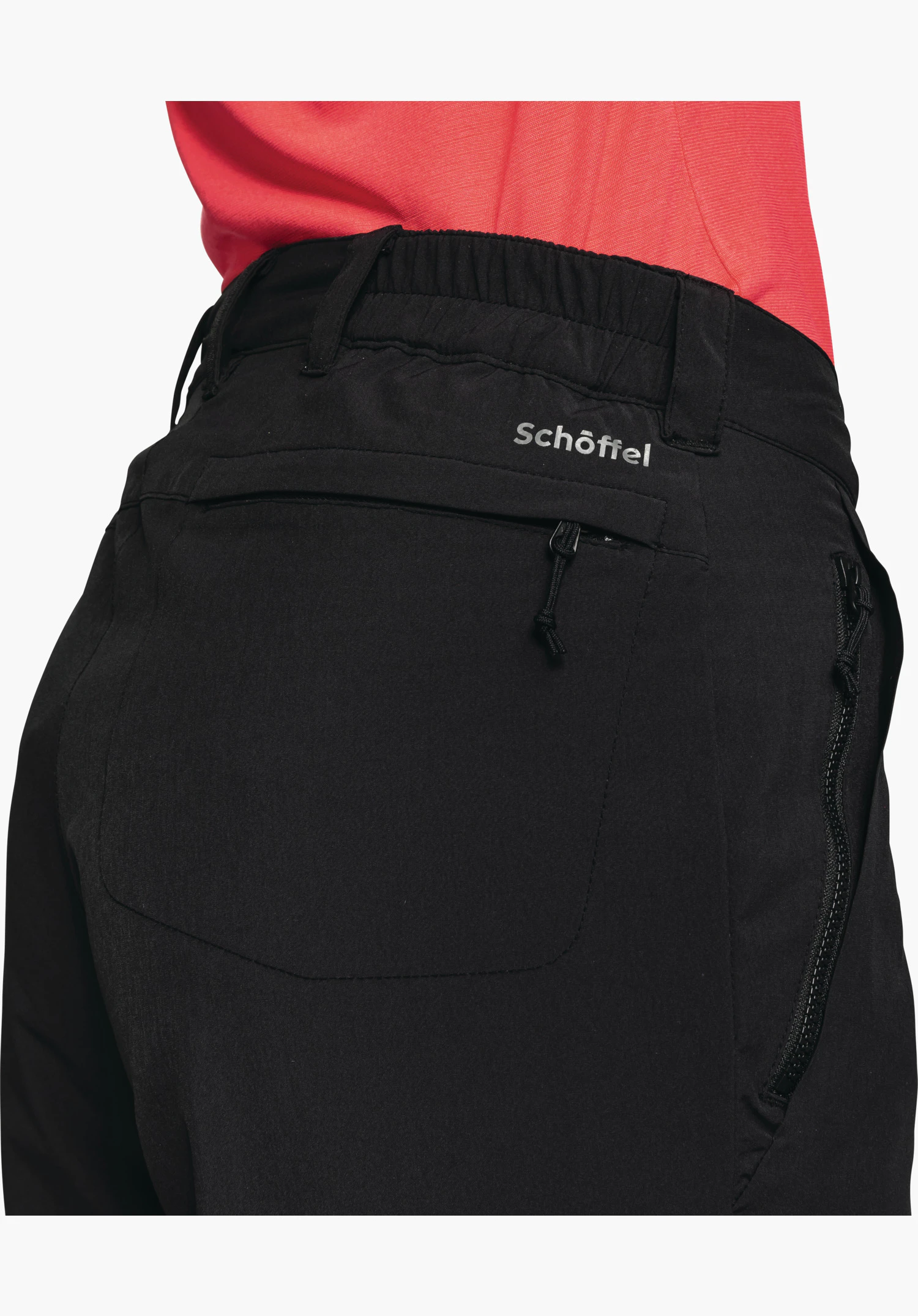 Pants Engadin1 Warm L zeigt den hinteren Hosenbund in Schwarz mit Gürtelschlaufen, elastischem Einsatz, der Reißverschlusstasche und dem Schöffel-Logo als Nahaufnahme vor weißem/neutralem Hintergrund.