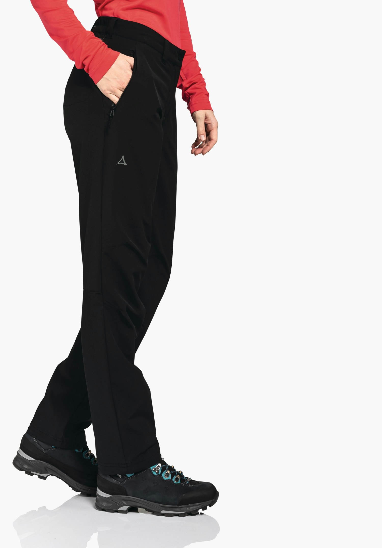 Pants Engadin1 Warm L black trousers with Schöffel logo on the outer thigh; person stands with one hand in the right pocket, wearing a light red long-sleeve shirt and black hiking shoes with blue details on a white background.