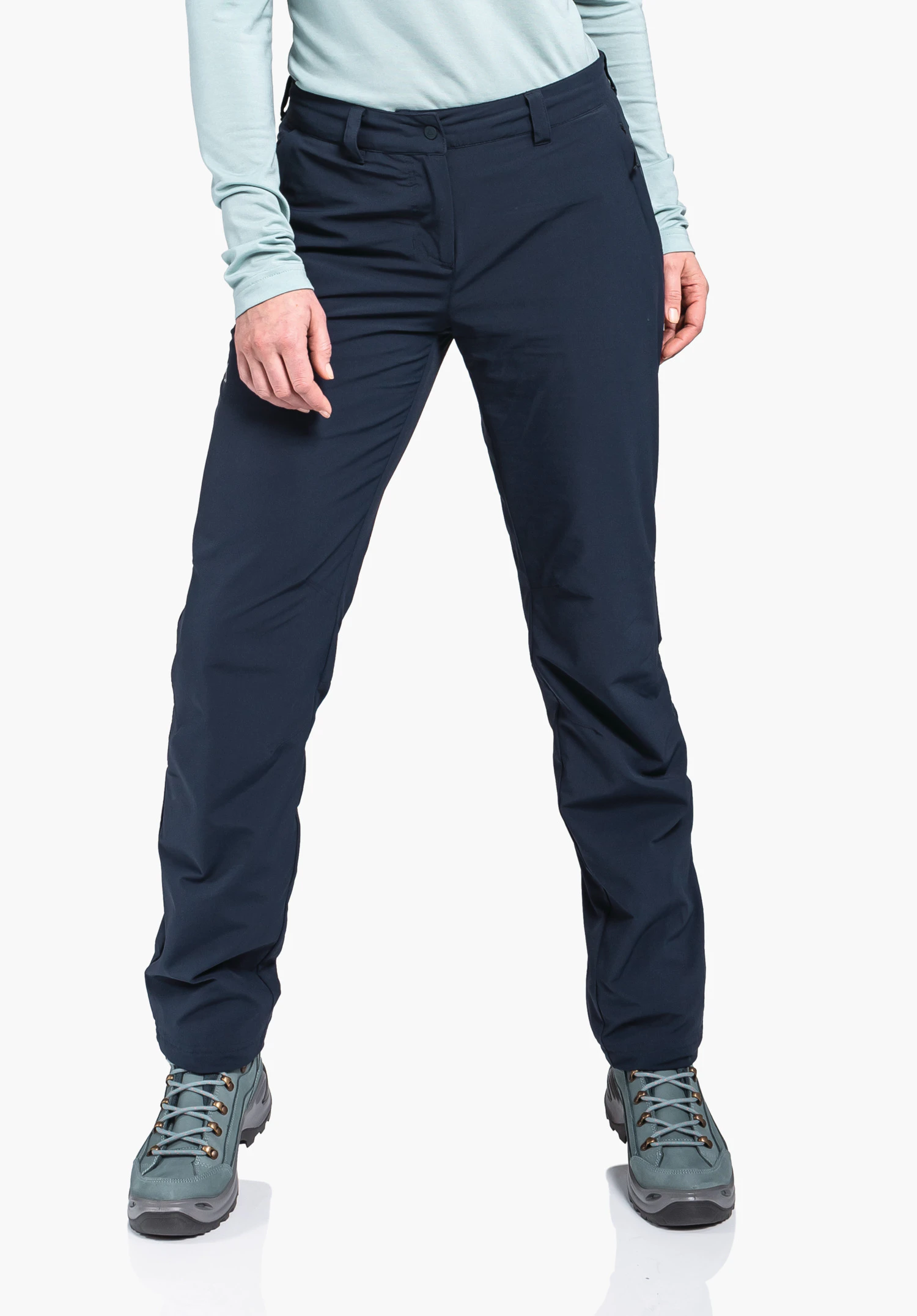 Pants Engadin1 Warm L dark blue women’s trousers, standing with legs slightly apart and hands at sides; context: light background, light blue top, light green hiking shoes.