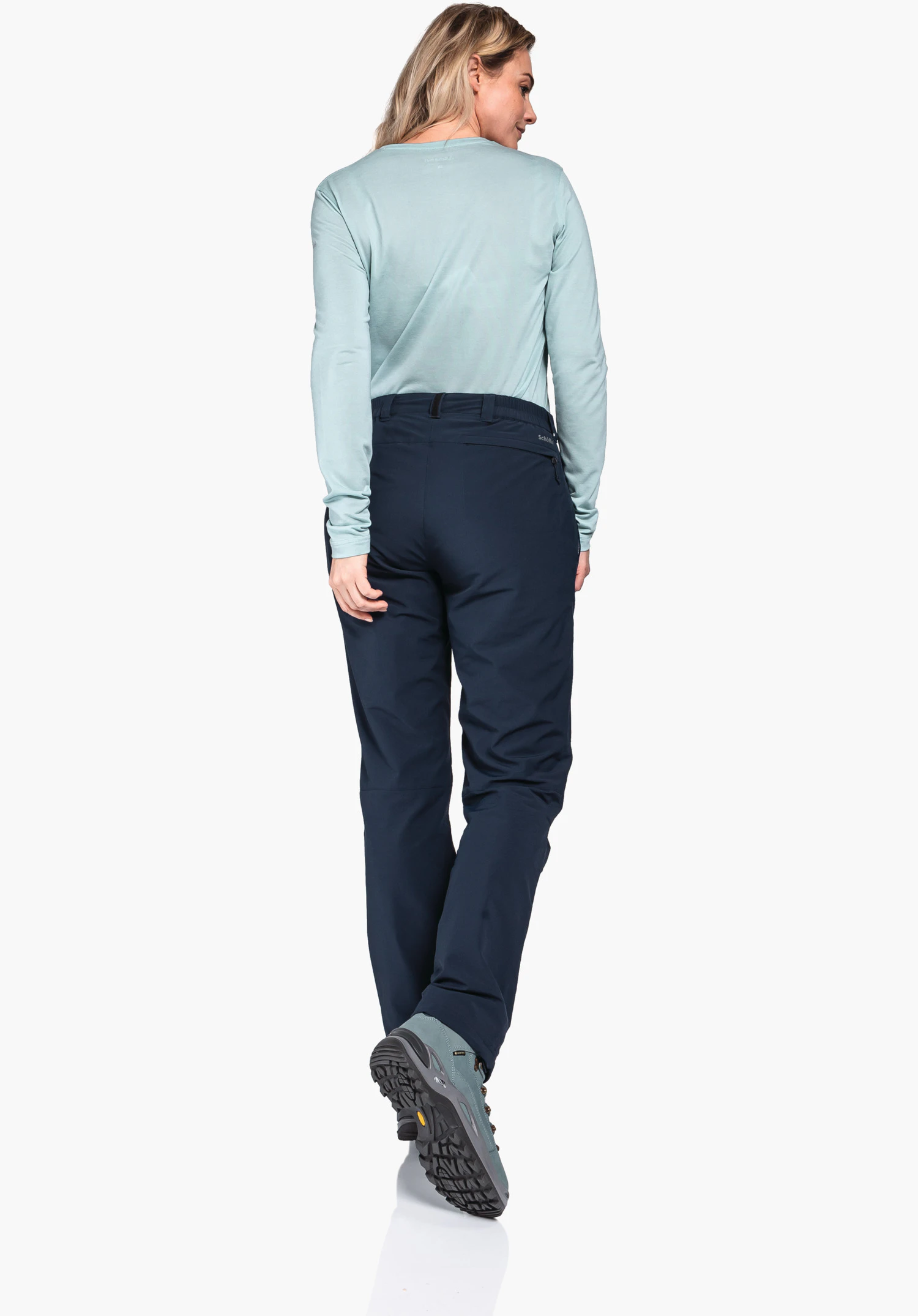 Pants Engadin1 Warm L, Detailansicht der Gesäßtasche mit Reißverschluss und des Schöffel-Logos auf dem blauen Material, Nahaufnahme vor weißem Hintergrund.