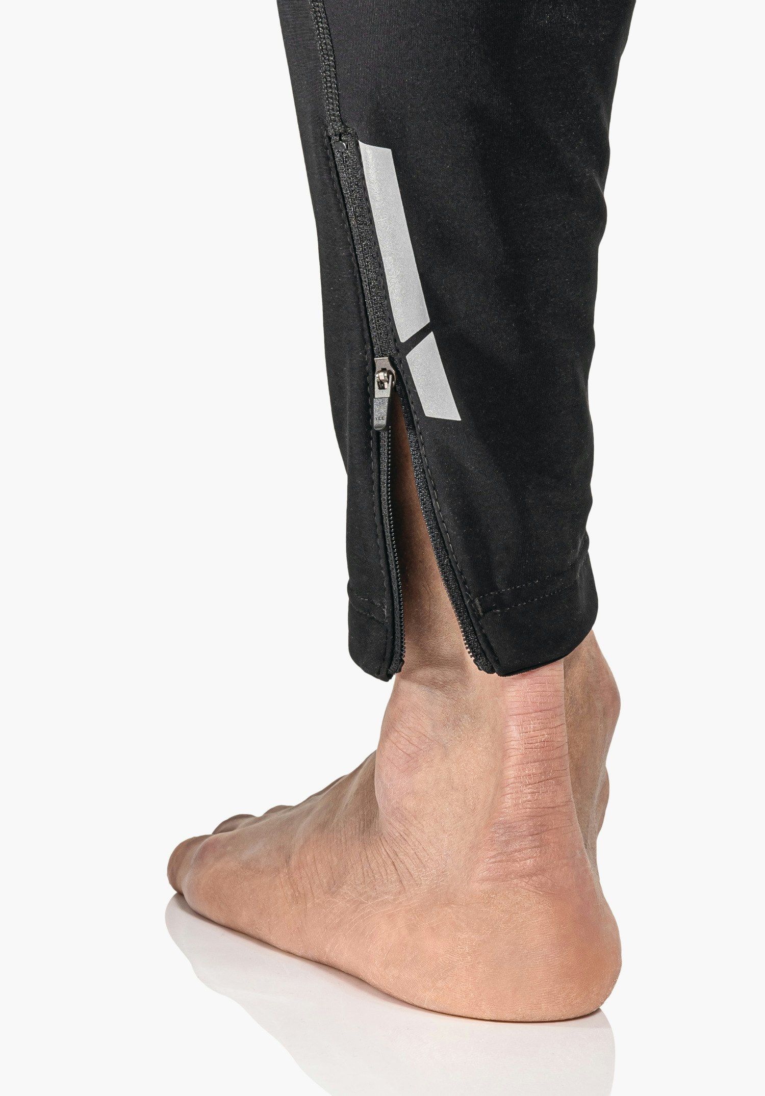 Skin Pants Warm 4h M, Detailansicht des verstellbaren Saums mit elastischem Kordelzug und Stopper in Schwarz, Nahaufnahme vor weißem/neutralem Hintergrund.