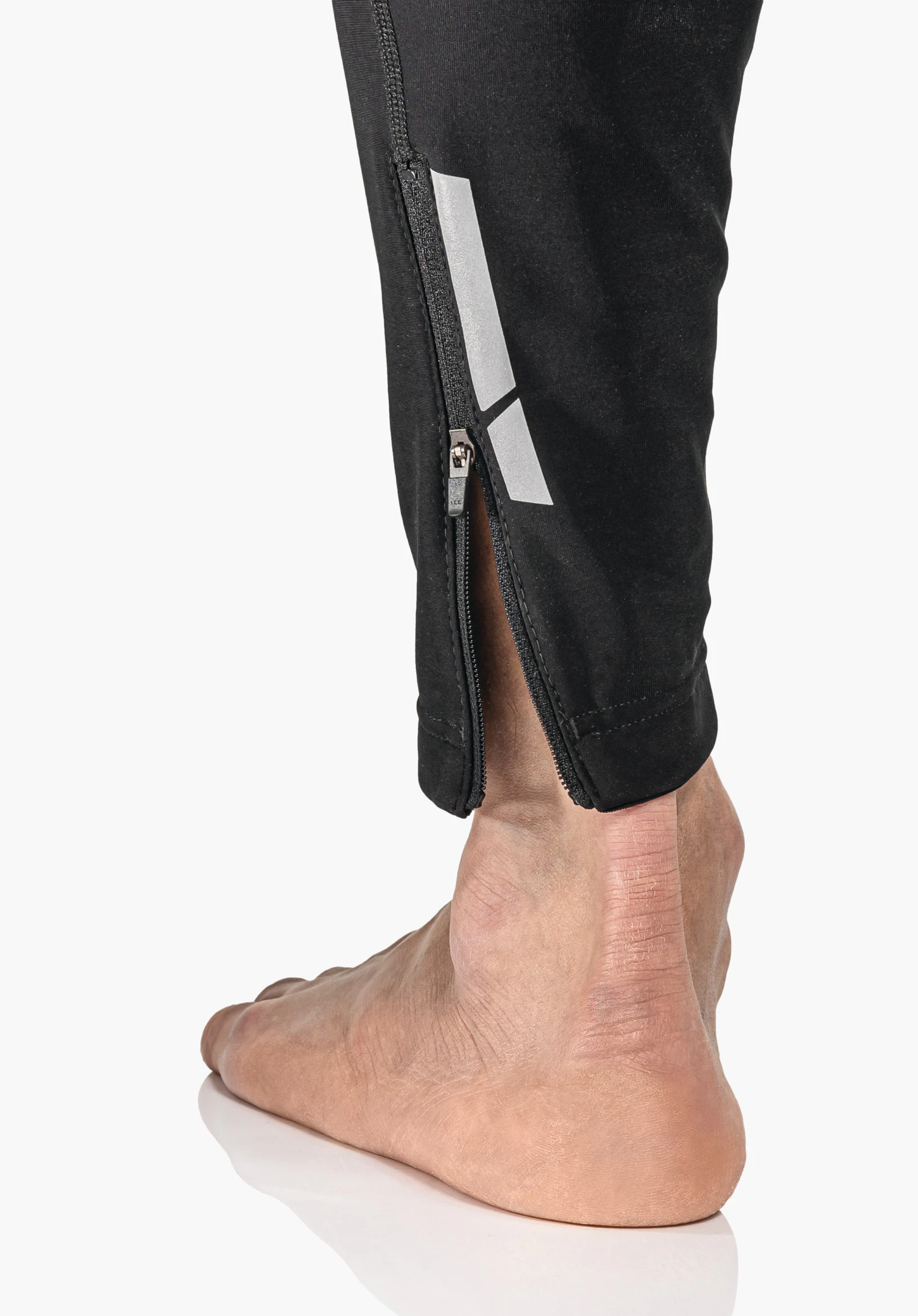 Skin Pants Warm 4h M, Detailansicht des verstellbaren Saums mit elastischem Kordelzug und Stopper in Schwarz, Nahaufnahme vor weißem/neutralem Hintergrund.
