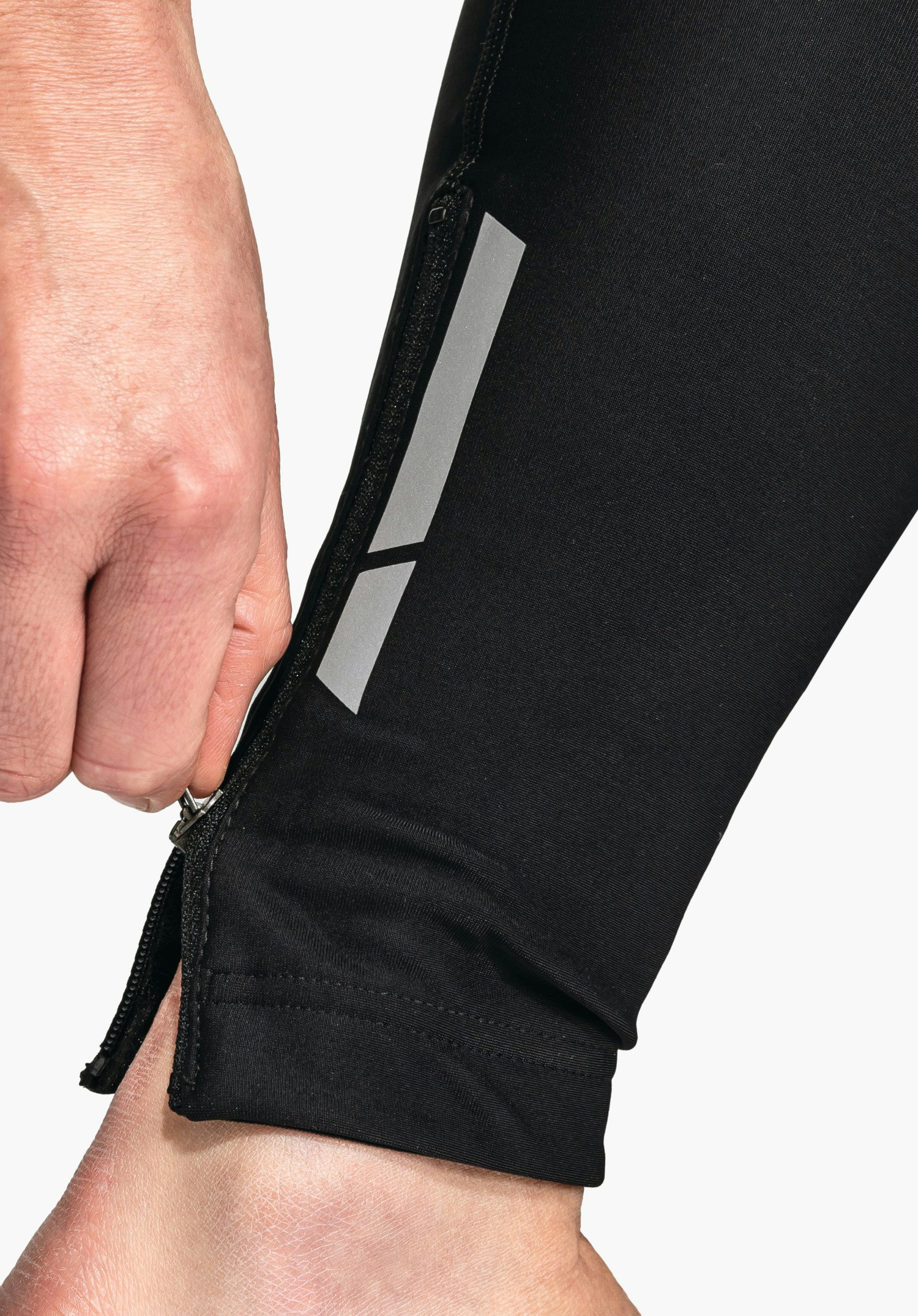 Skin Pants Warm 4h L vue détaillée du bas de jambe noir avec fermeture éclair et bandes réfléchissantes, gros plan sur fond blanc.