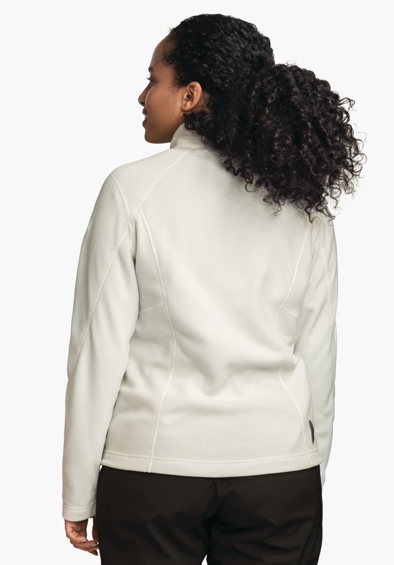 Fleece Jacket Leona3 off-white fleece jacket worn by a person from the back; person looks sideways over the shoulder; black curly hair, dark brown trousers; light neutral background.