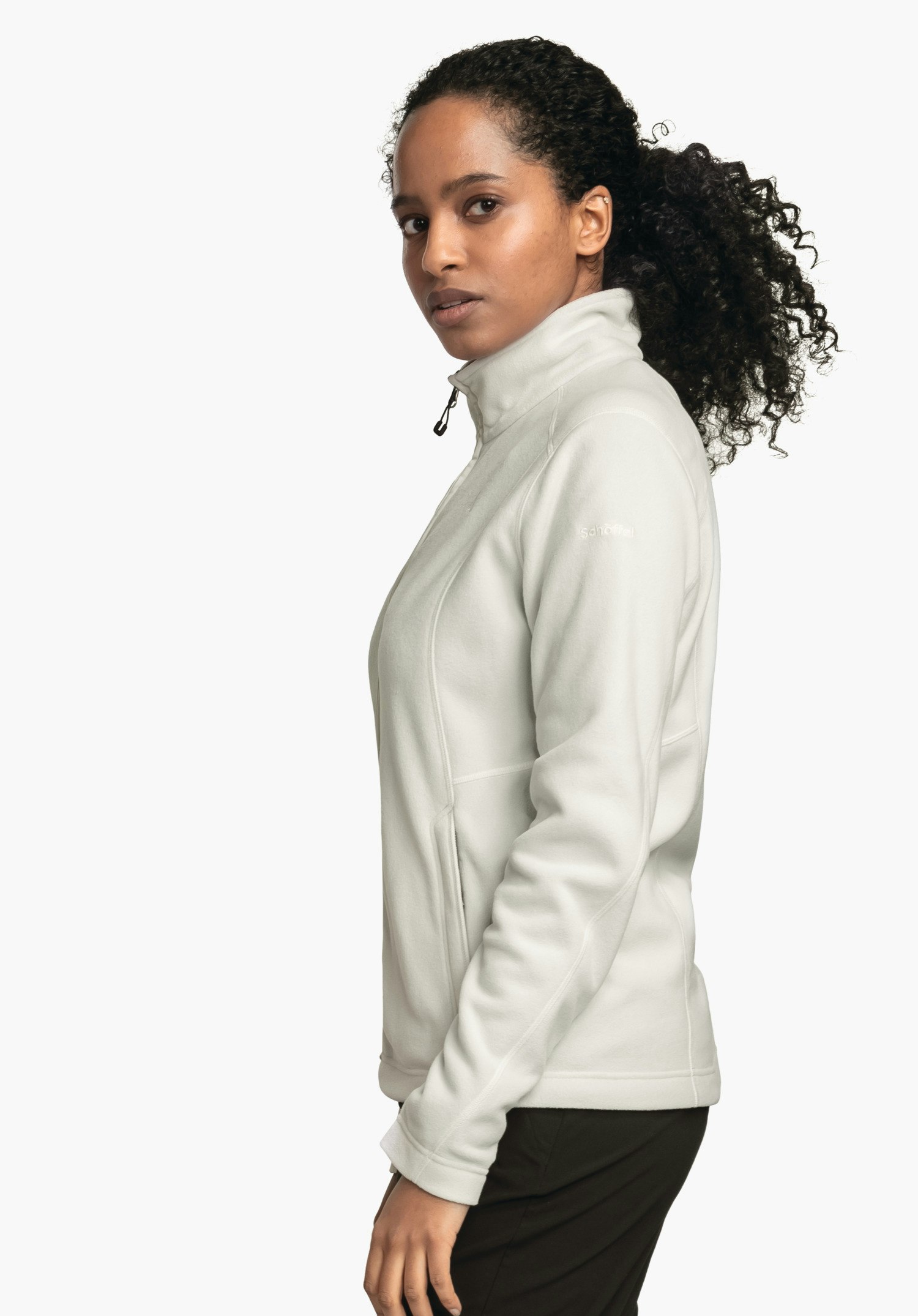 Fleece Jacket Leona3 jas: vrouw draagt een lichtwitte fleecejas met opstaande kraag, staat zijwaarts en kijkt naar de camera voor een effen witte achtergrond. Tekst: "schöffel".