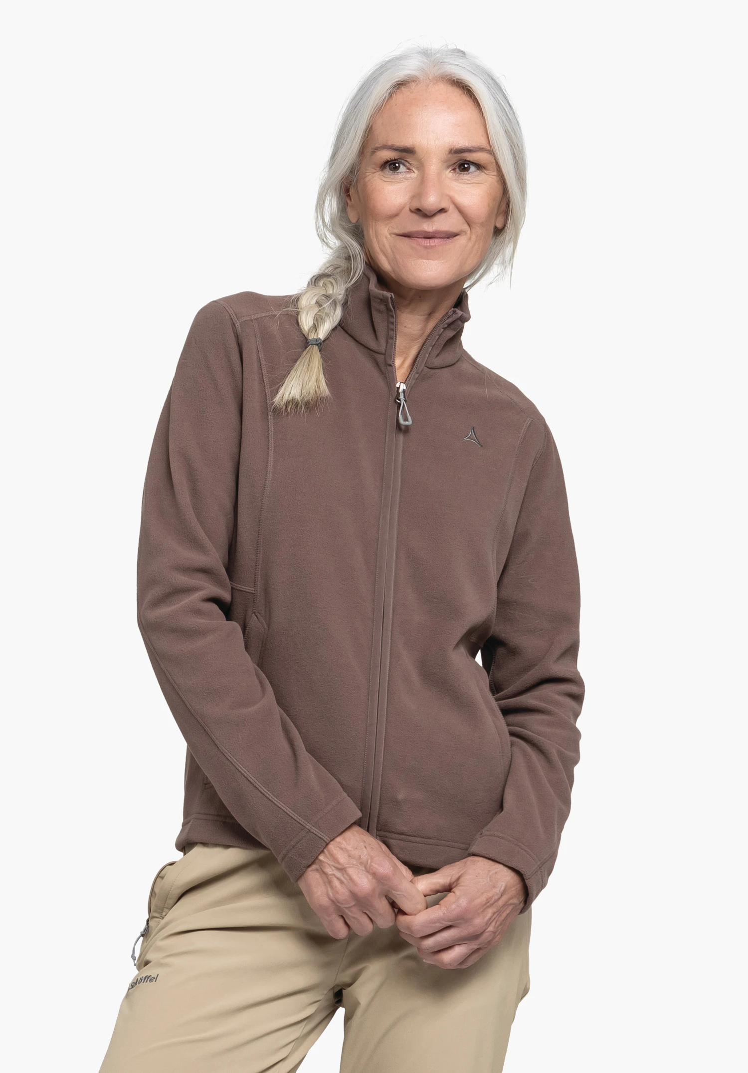 Fleece Jacket Leona3 an einem Model, das mit gefalteten Händen steht. Die braune Jacke zeigt das Schöffel-Logo auf der linken Brust und wird vor einem neutralen Hintergrund präsentiert.