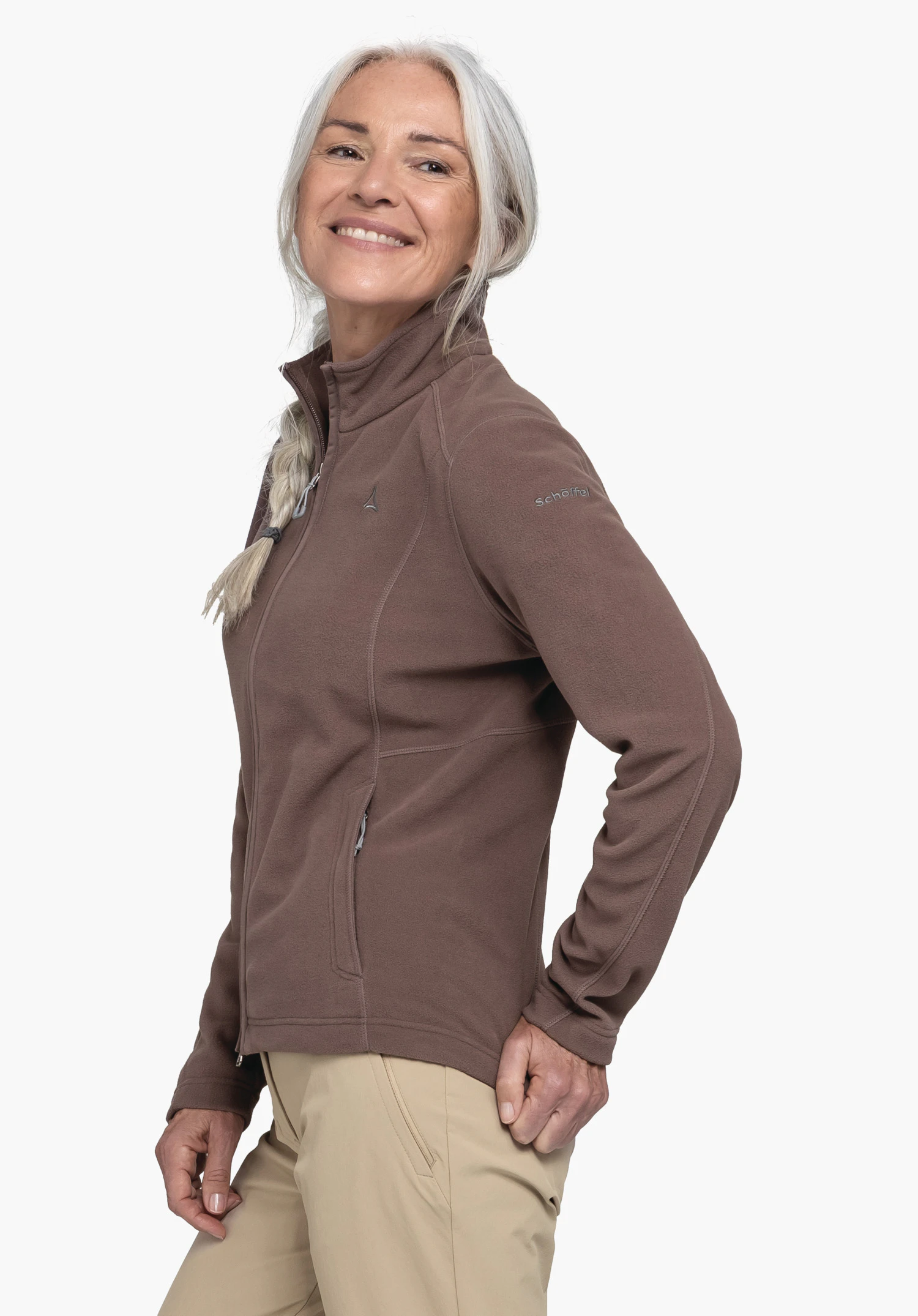 Fleece Jacket Leona3 an einem Model, das seitlich steht. Die Fleecejacke in Braun zeigt das Schöffel-Logo auf der Brust und am Ärmel, präsentiert vor einem neutralen Hintergrund.