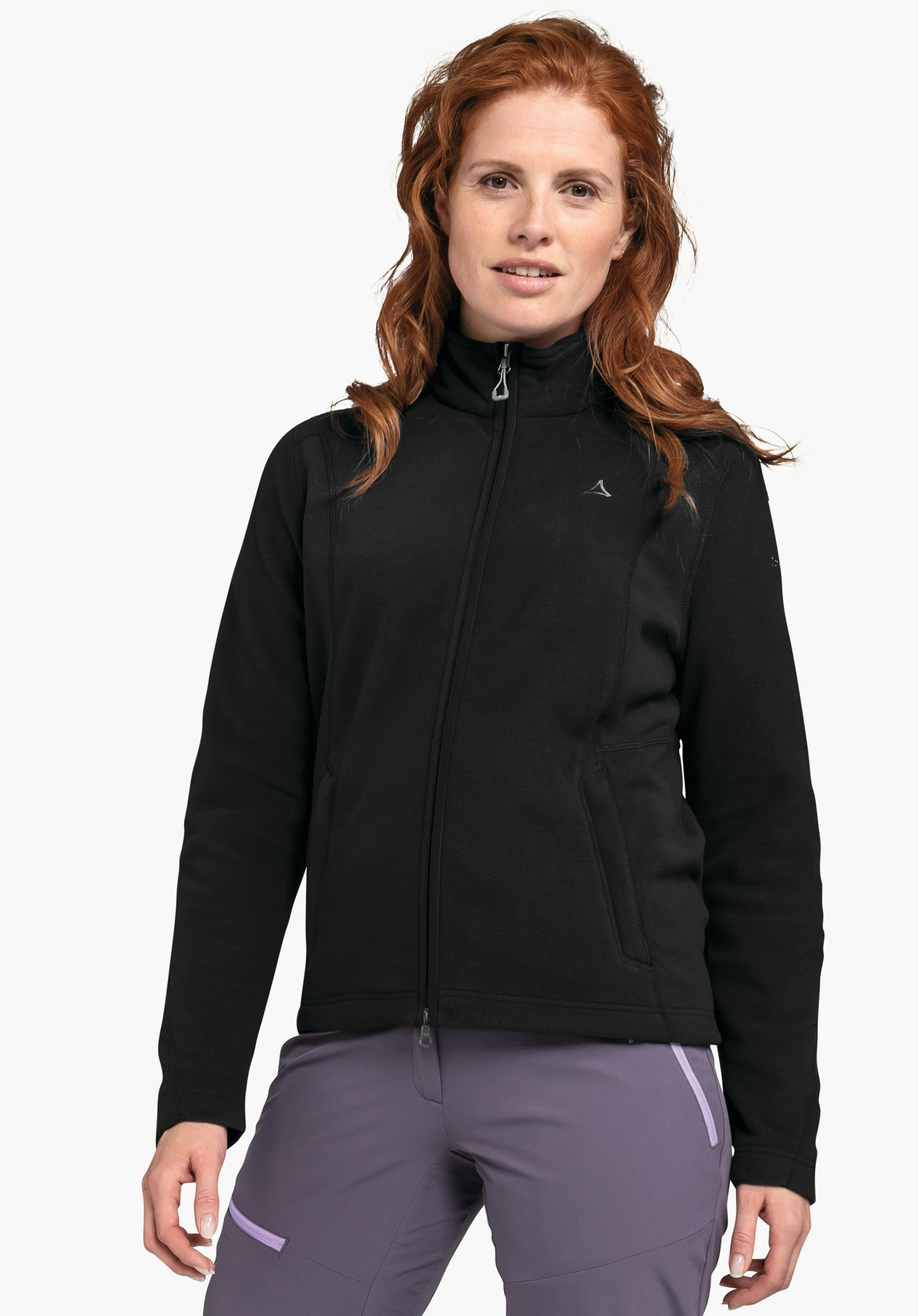 Fleece Jacket Leona3 Veste polaire noire portée par une femme aux cheveux roux, debout de face; logo Schöffel sur la poitrine; fond studio blanc.