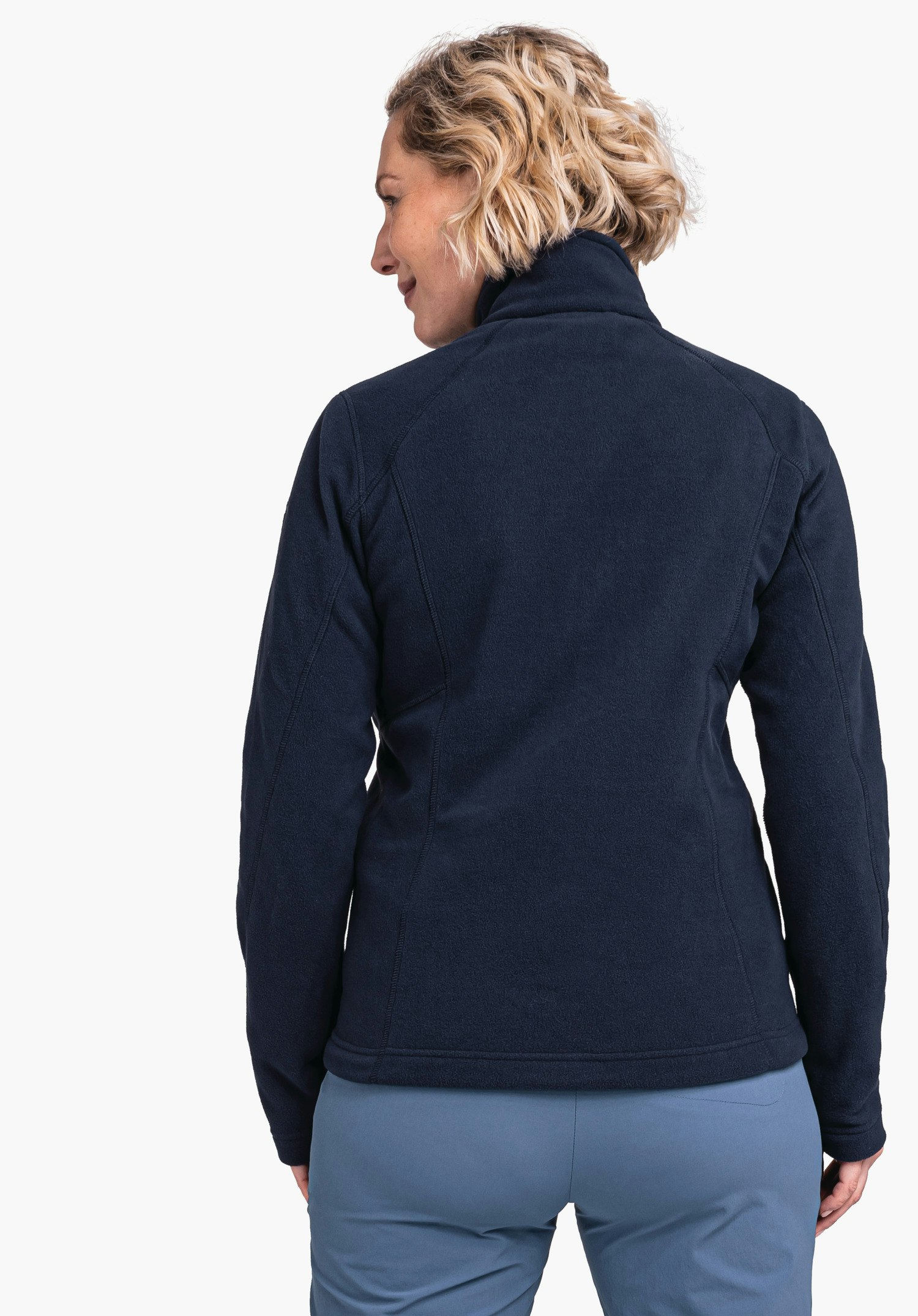 Fleece Jacket Leona3 dark blue fleece jacket; person stands with back to the camera, head slightly turned left; wearing light blue trousers; neutral background.