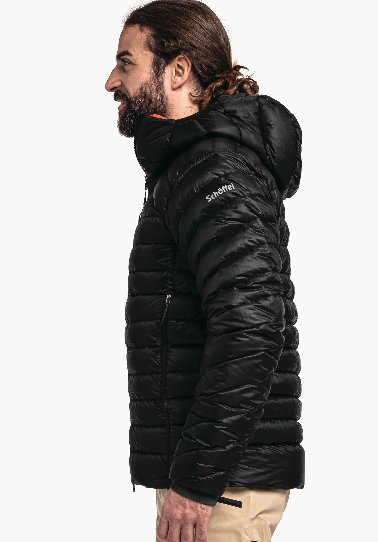 Down Jacket Silvretta M black down jacket worn by a man standing side-on and looking left, hood raised, in front of a white background. Text on sleeve: "Schöffel".
