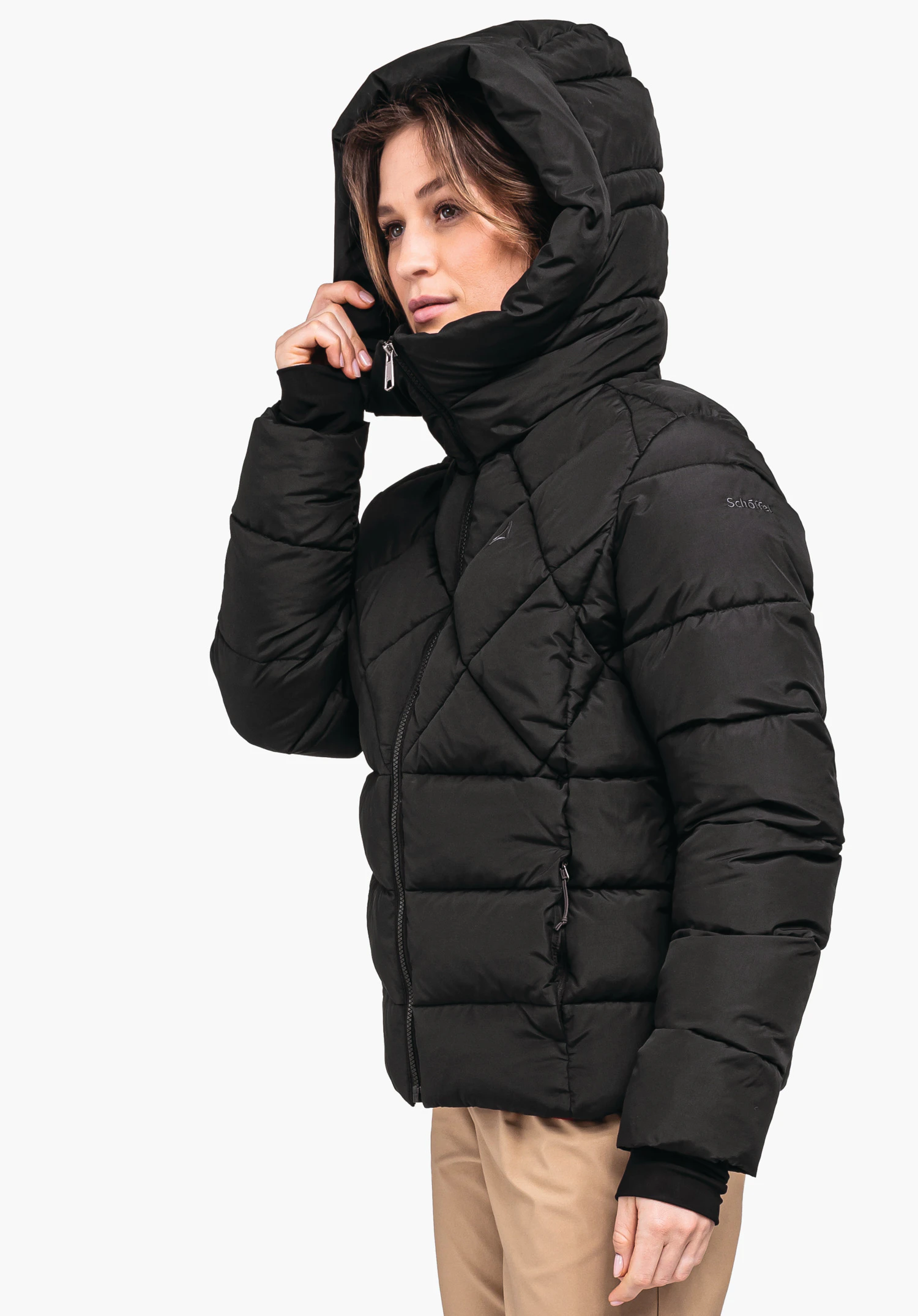 Ins Jacket Boston L black quilted jacket; woman pulls up the hood, side zip pockets, sporty fit in front of a neutral background. Text: "Schöffel" on sleeve, Schöffel logo on chest.