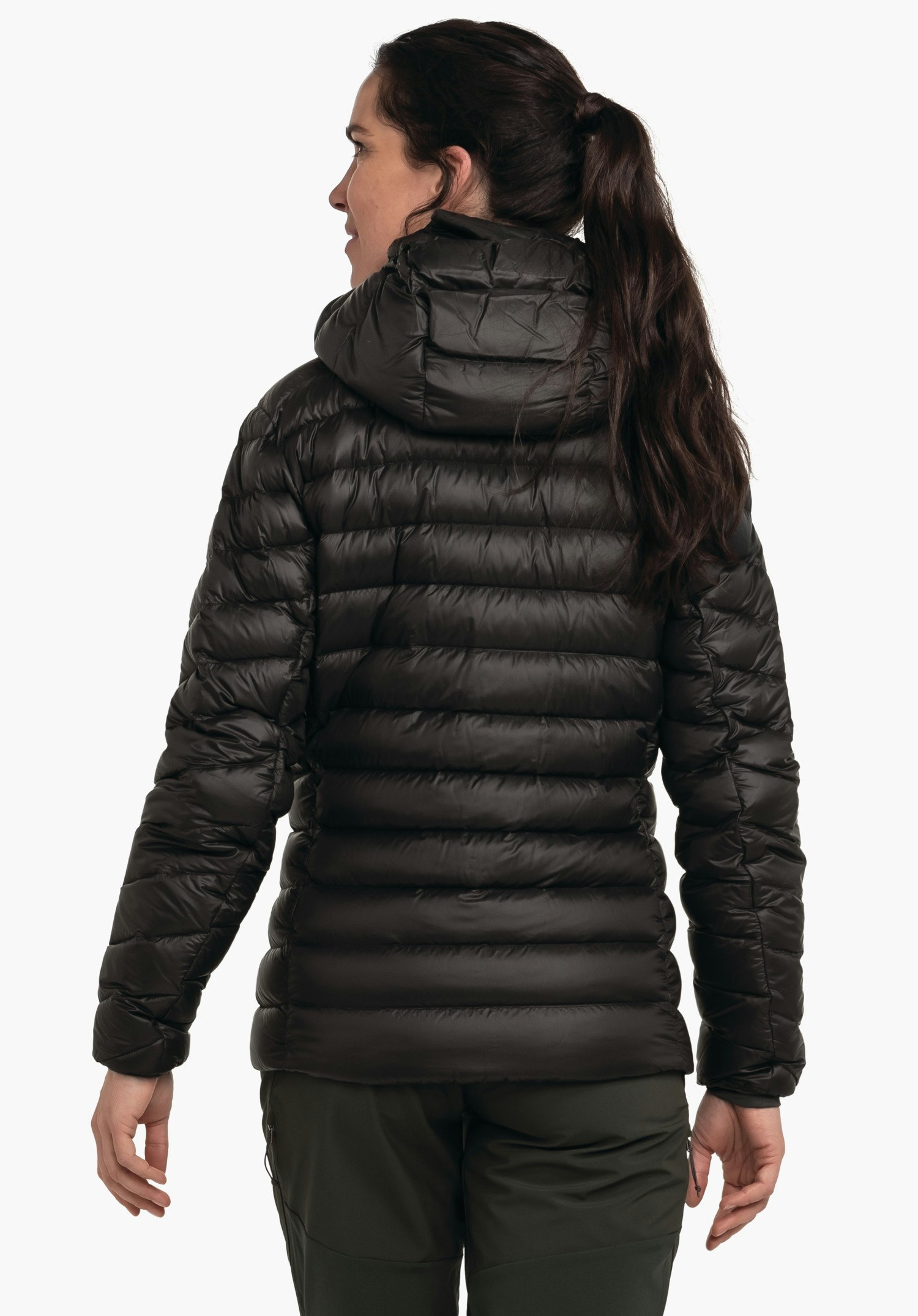 Down Jacket Silvretta L doudoune noire portée de dos par une personne debout; capuche et matelassage horizontal visibles; contexte: fond studio blanc, pantalon vert foncé.