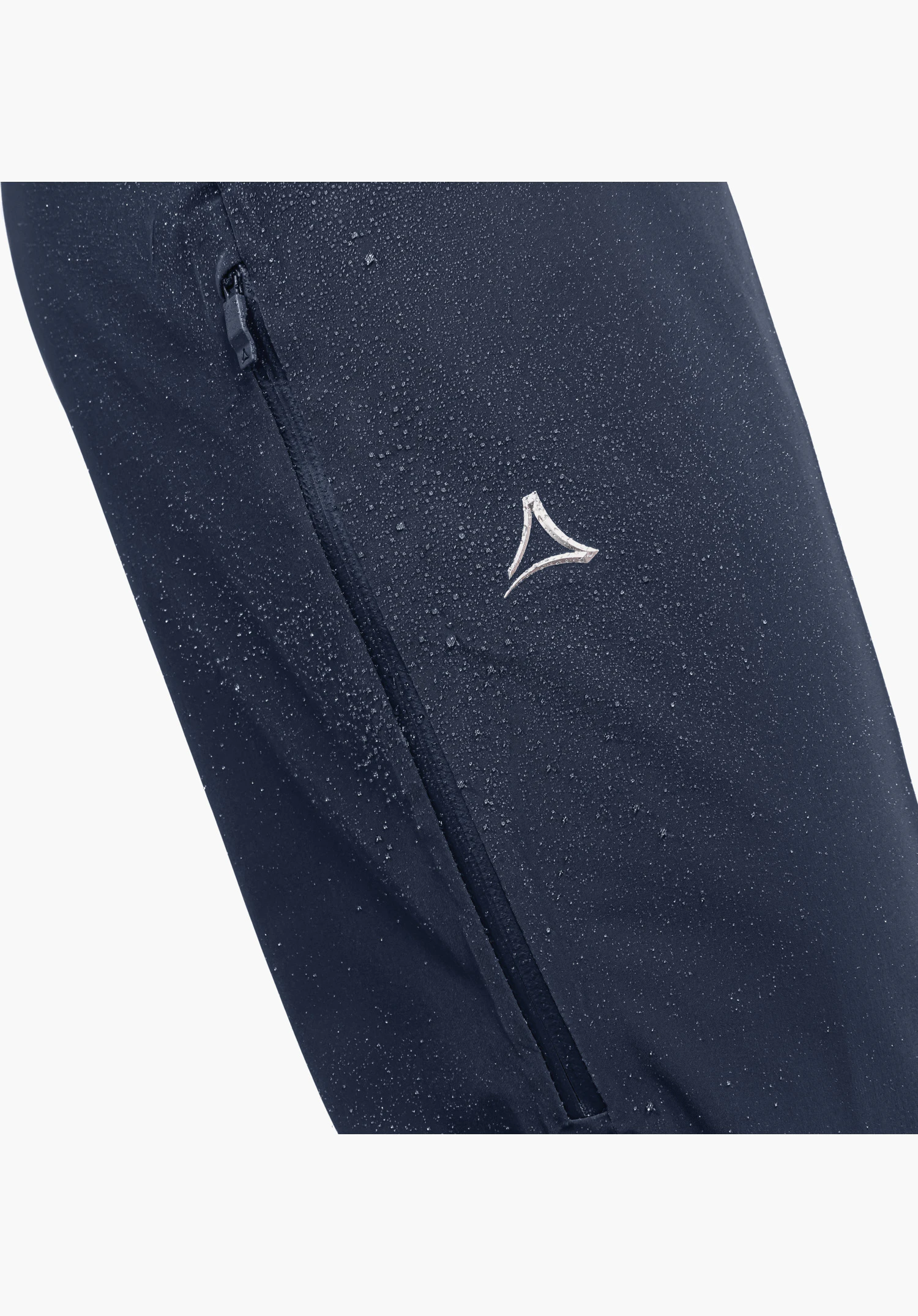 Ski Pants Trevalli M présente un tissu bleu déperlant avec des gouttelettes d'eau, une fermeture éclair et le logo Schöffel argenté. Gros plan sur fond blanc.