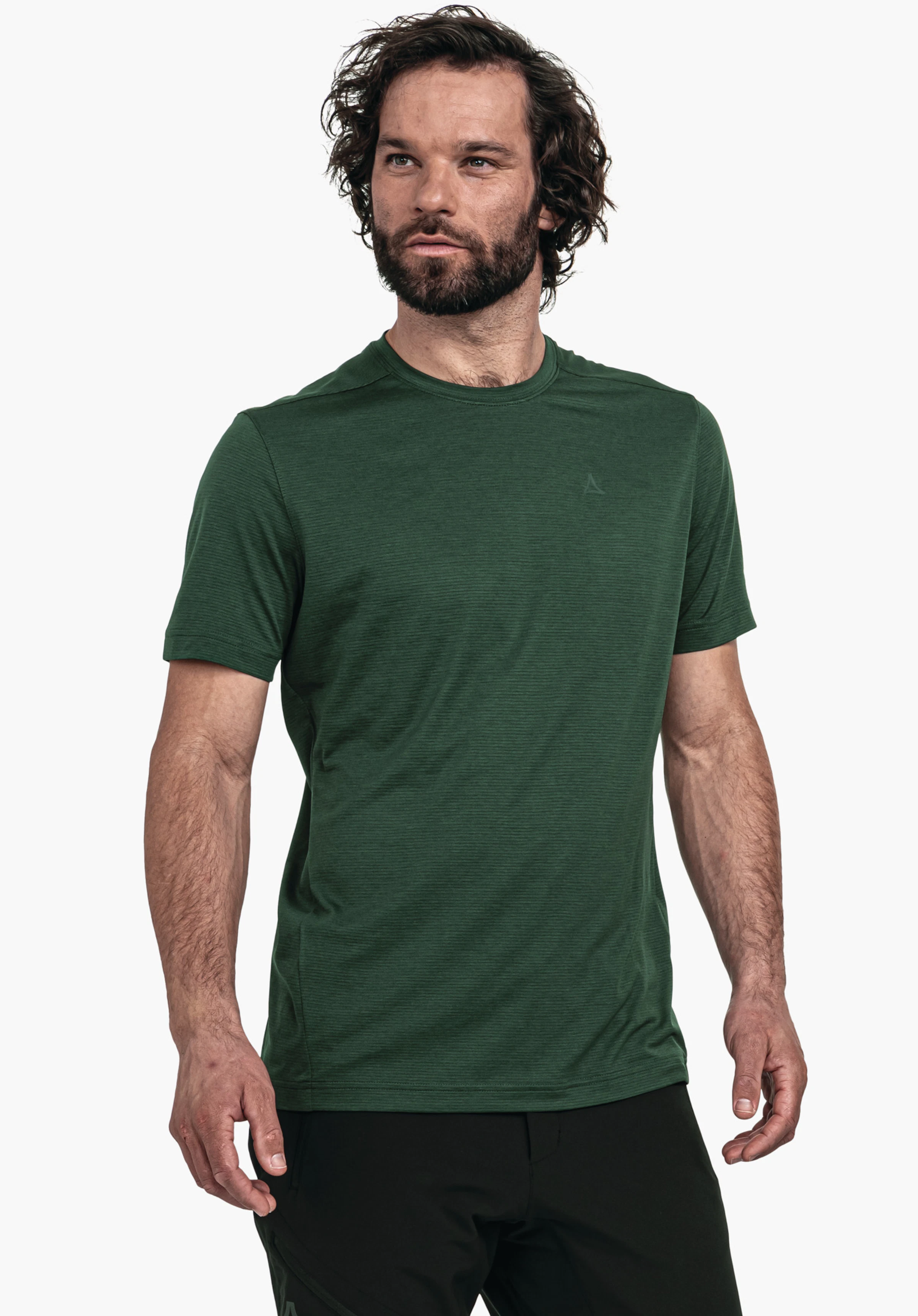 CIRC T Shirt Tauron M T-shirt vert foncé avec logo Schöffel; porté par un homme légèrement de côté regardant vers la droite; manches courtes, barbe, cheveux bouclés; fond blanc lumineux.