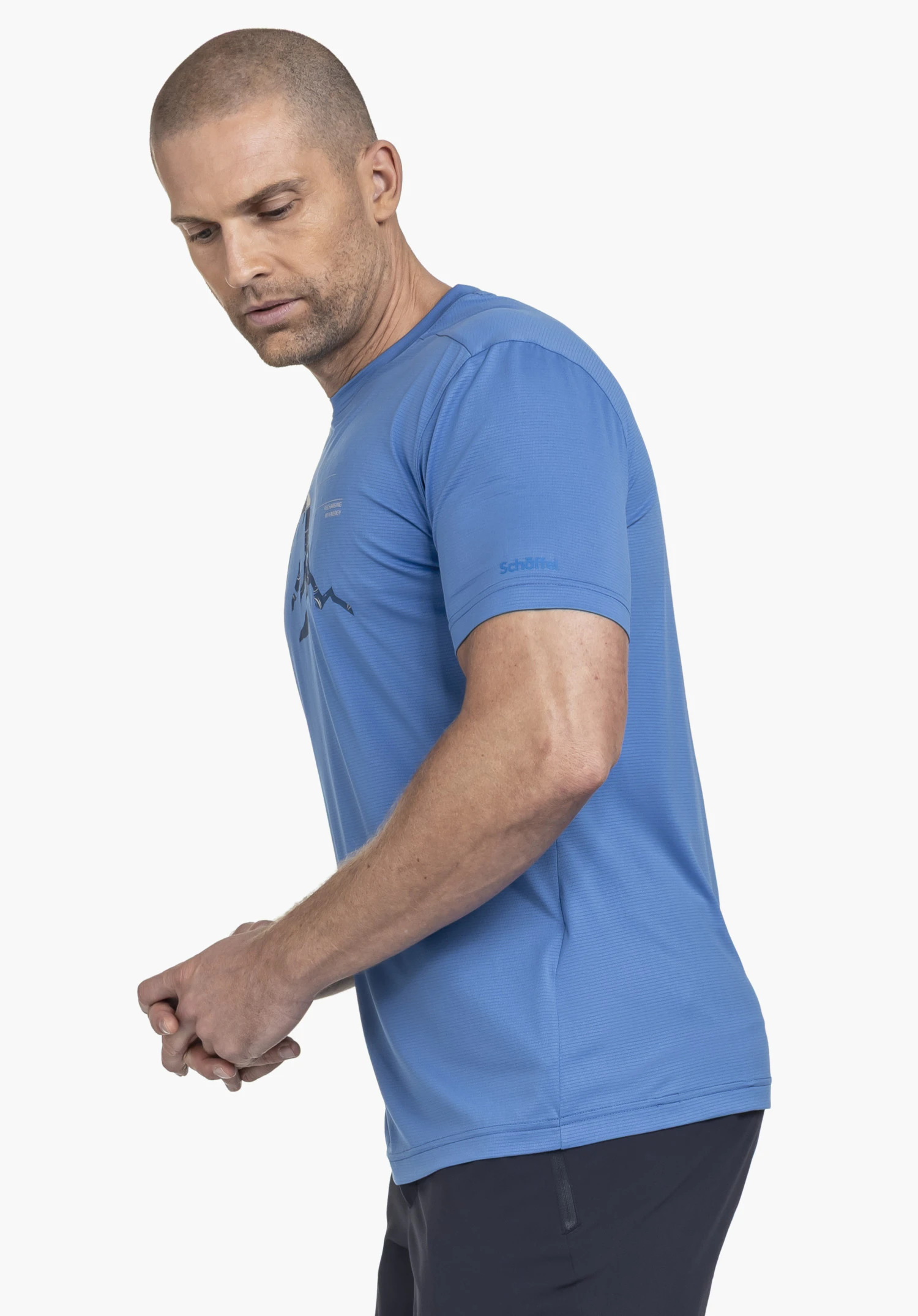 CIRC T Shirt Sulten M: Der männliche Körper ist in einer seitlichen Pose vor einem neutralen Hintergrund zu sehen. Das blaue T-Shirt zeigt den dynamischen Schnitt und das auf dem Ärmel platzierte Schöffel-Logo.