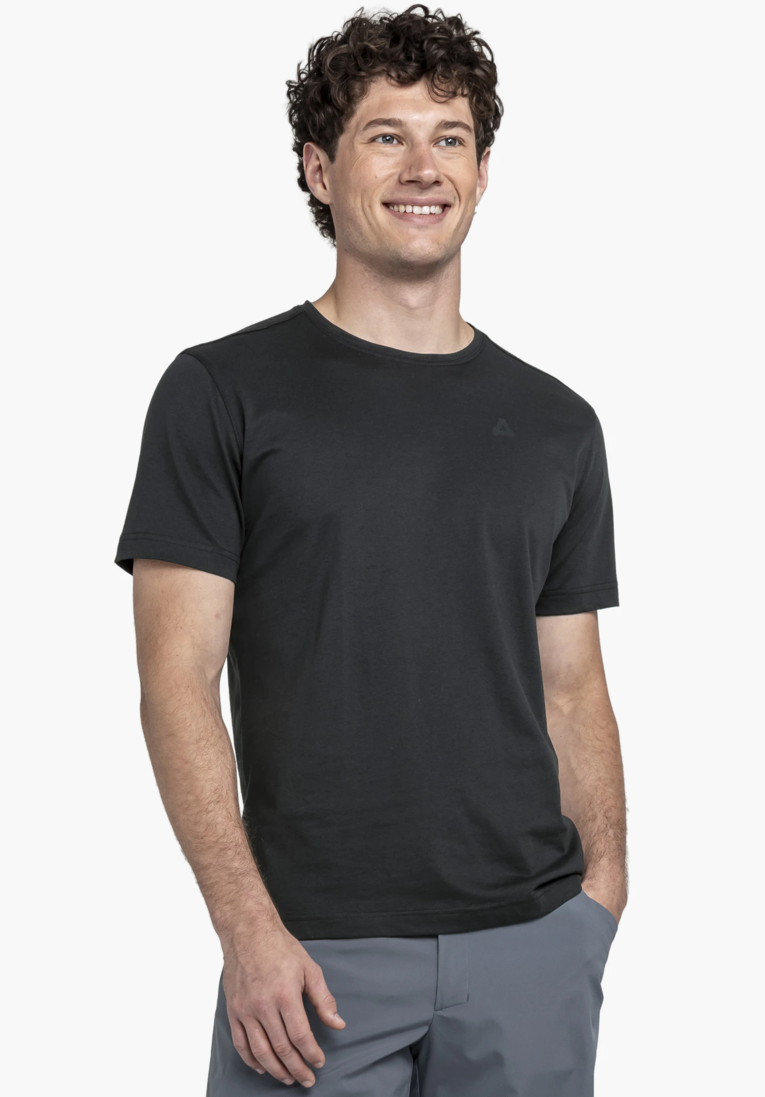 T Shirt Buchberg M in classic black. The model stands front-on, smiling, in front of a neutral background. The Schöffel logo is subtly placed on the chest.