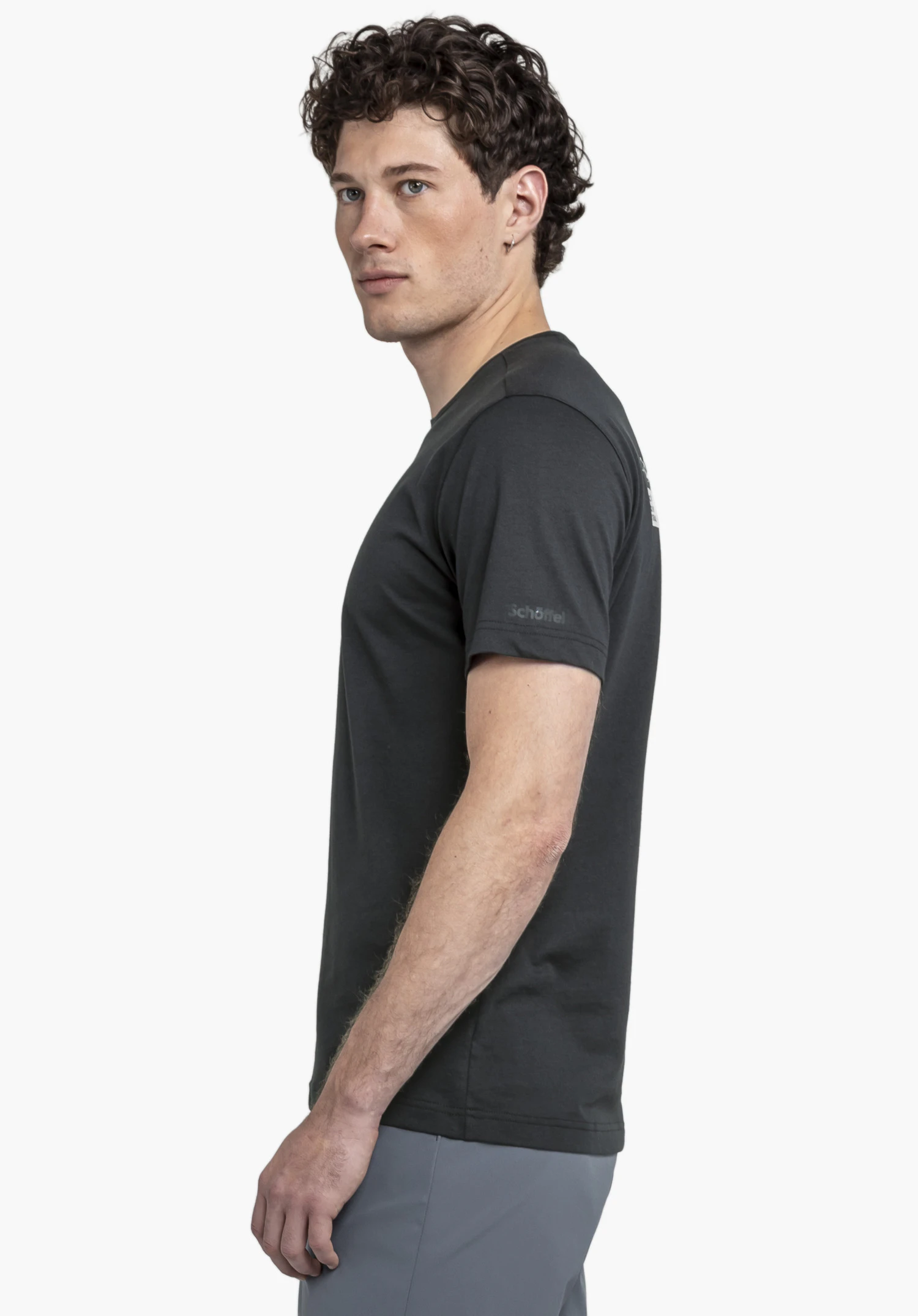 T Shirt Buchberg M in classic black worn by a model standing sideways to the camera. The t-shirt features the subtle, tonal Schöffel logo on the sleeve. The shot is taken against a neutral background.