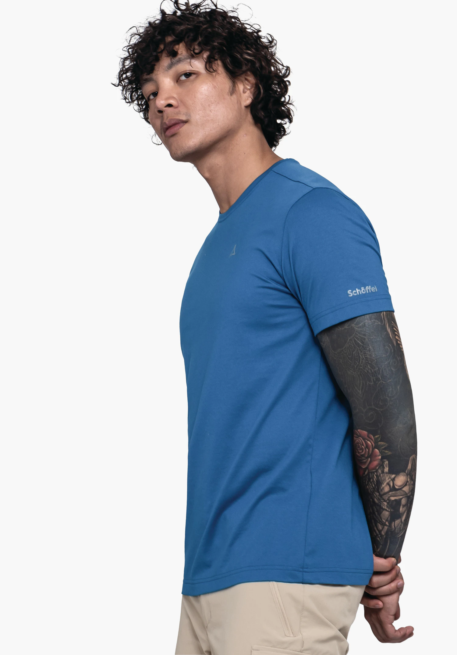 T Shirt Hohberg M in blue. The model stands sideways in front of a neutral background, showcasing the shirt. The sleeve area clearly displays the subtle Schöffel logo.