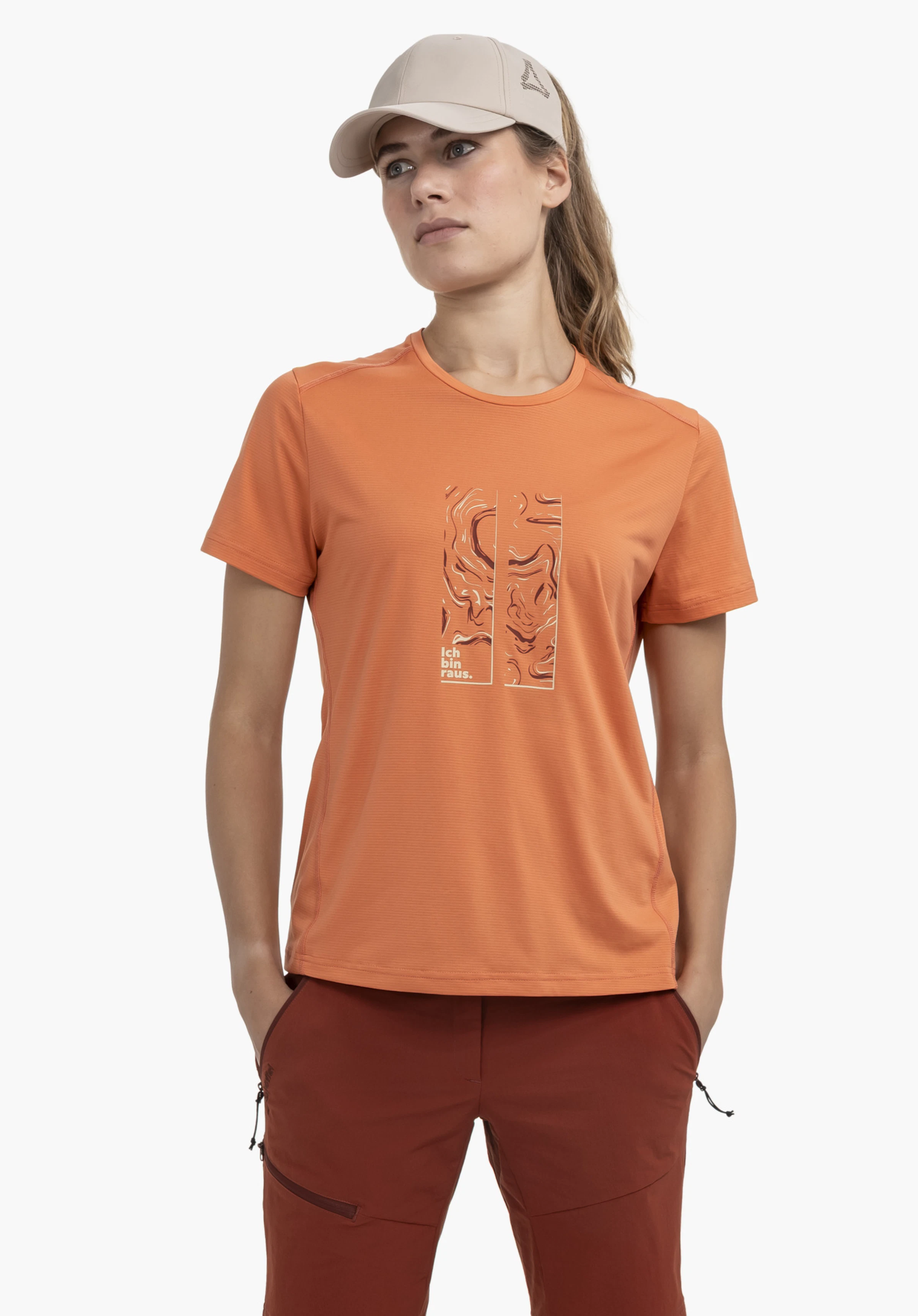CIRC T Shirt Sulten L. Een model staat frontaal, kijkt iets opzij en draagt het oranje t-shirt met een opvallende grafische print op de borst tegen een neutrale achtergrond.