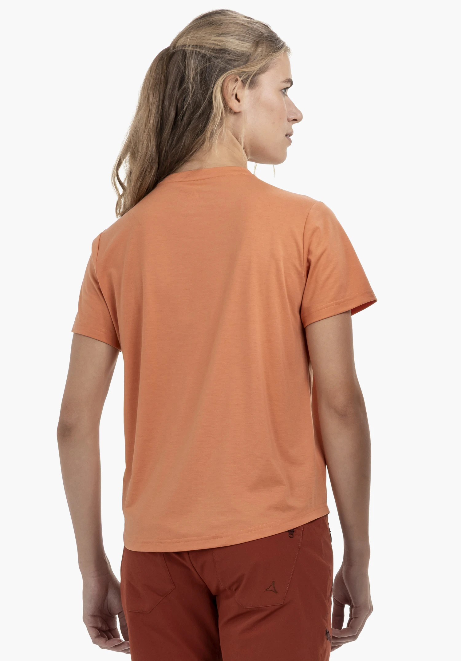 T Shirt Haberspitz L in orange. The model is shown from the back wearing the shirt against a neutral background. The trousers feature a subtle Schöffel logo.