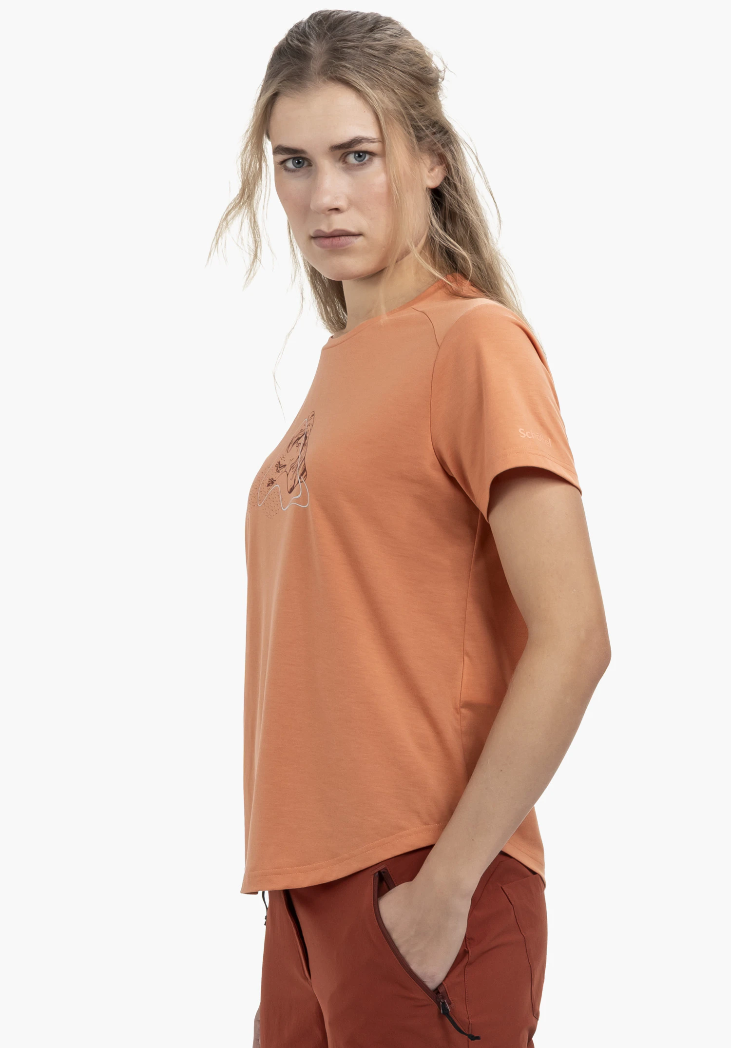 T Shirt Haberspitz L in orange: The model stands sideways against a neutral background, wearing the shirt featuring a subtle Schöffel logo on the sleeve, highlighting the sporty look.