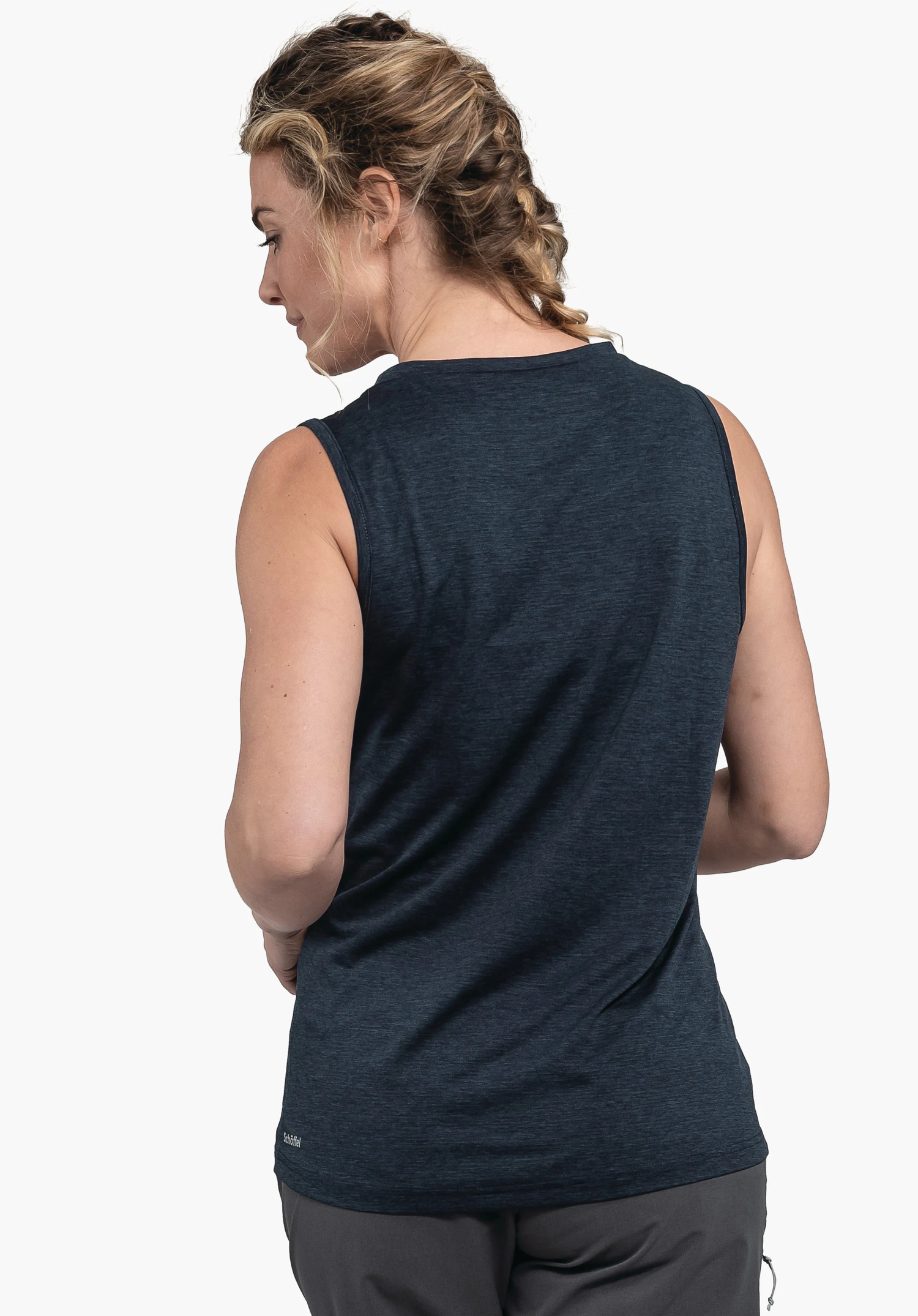 CIRC Top Tauron L gedragen door een model in rugaanzicht. Je ziet de blauwe top, waarbij linksonder op de zoom het kleine Schöffel-logo zichtbaar is. Het model staat voor een neutrale achtergrond en kijkt opzij.
