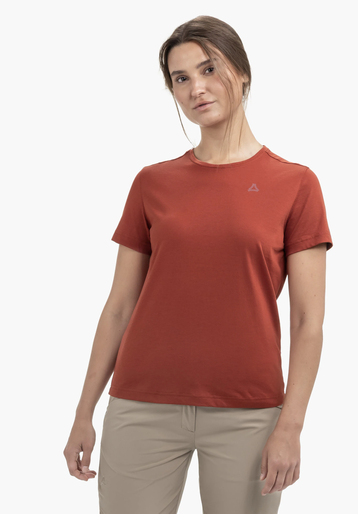 T Shirt Buchberg L en rouge. Le mannequin se tient de face devant un fond neutre et porte le t-shirt à manches courtes avec le logo Schöffel sur la poitrine gauche avec un pantalon beige.